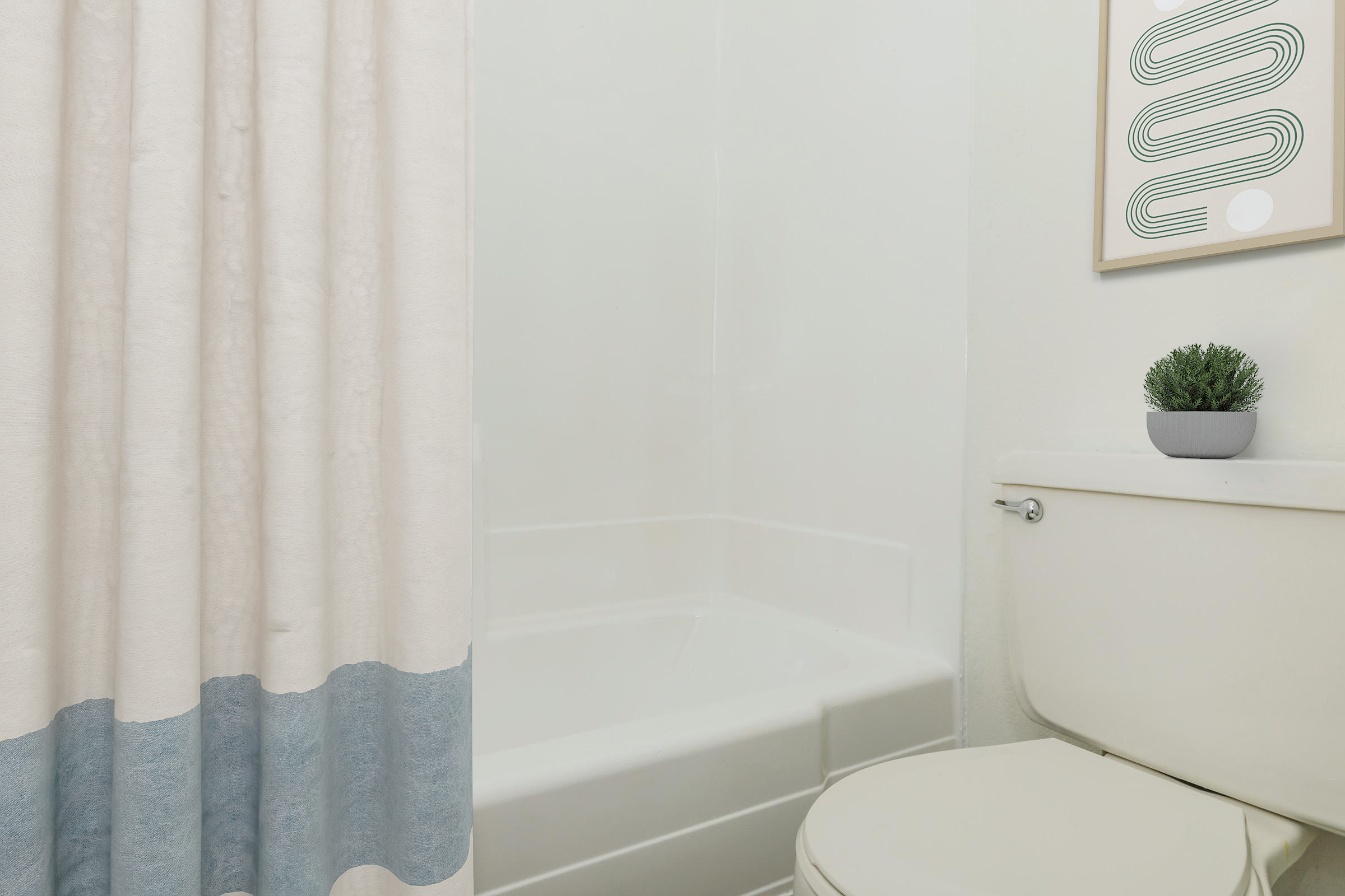 A clean bathroom scene featuring a bathtub with a shower curtain, a toilet, and a decorative plant on the toilet tank. The wall is painted white, and a minimalist framed artwork is visible in the background, adding a touch of style to the space.