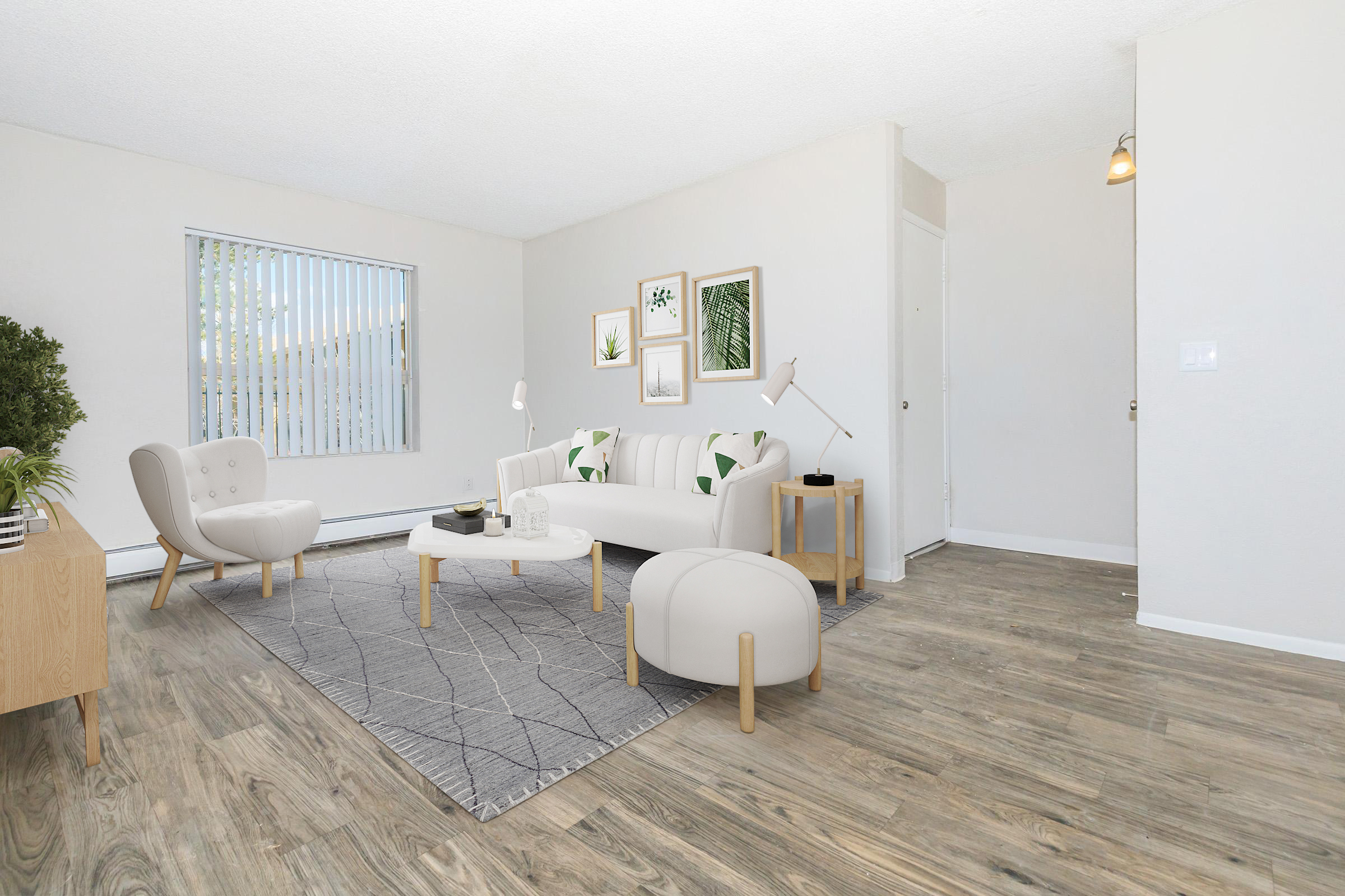 A bright and modern living room featuring a light-colored sofa and armchair, a round coffee table, and a decorative rug. The walls are adorned with framed plant art. Large windows provide natural light, and the flooring has a wood-like finish, creating a warm and inviting atmosphere.
