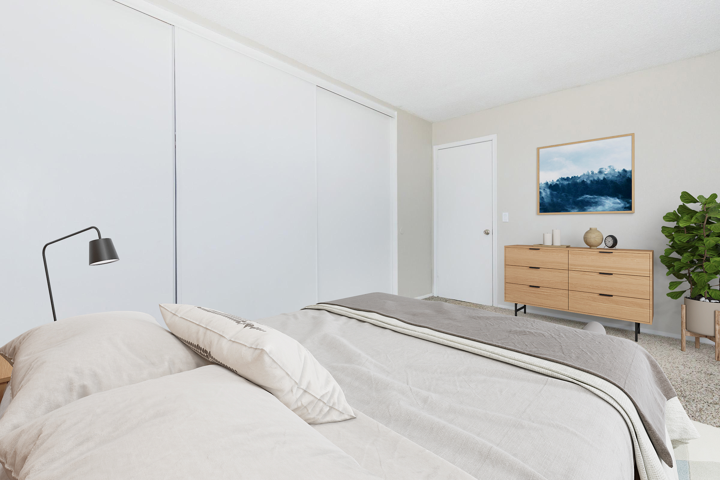 A modern bedroom featuring a cozy bed with neutral-colored bedding, a minimalist nightstand lamp, a wooden dresser with decorative items, and a large plant. The walls are painted in soft tones, and a piece of landscape art hangs above the dresser, adding to the tranquil atmosphere.