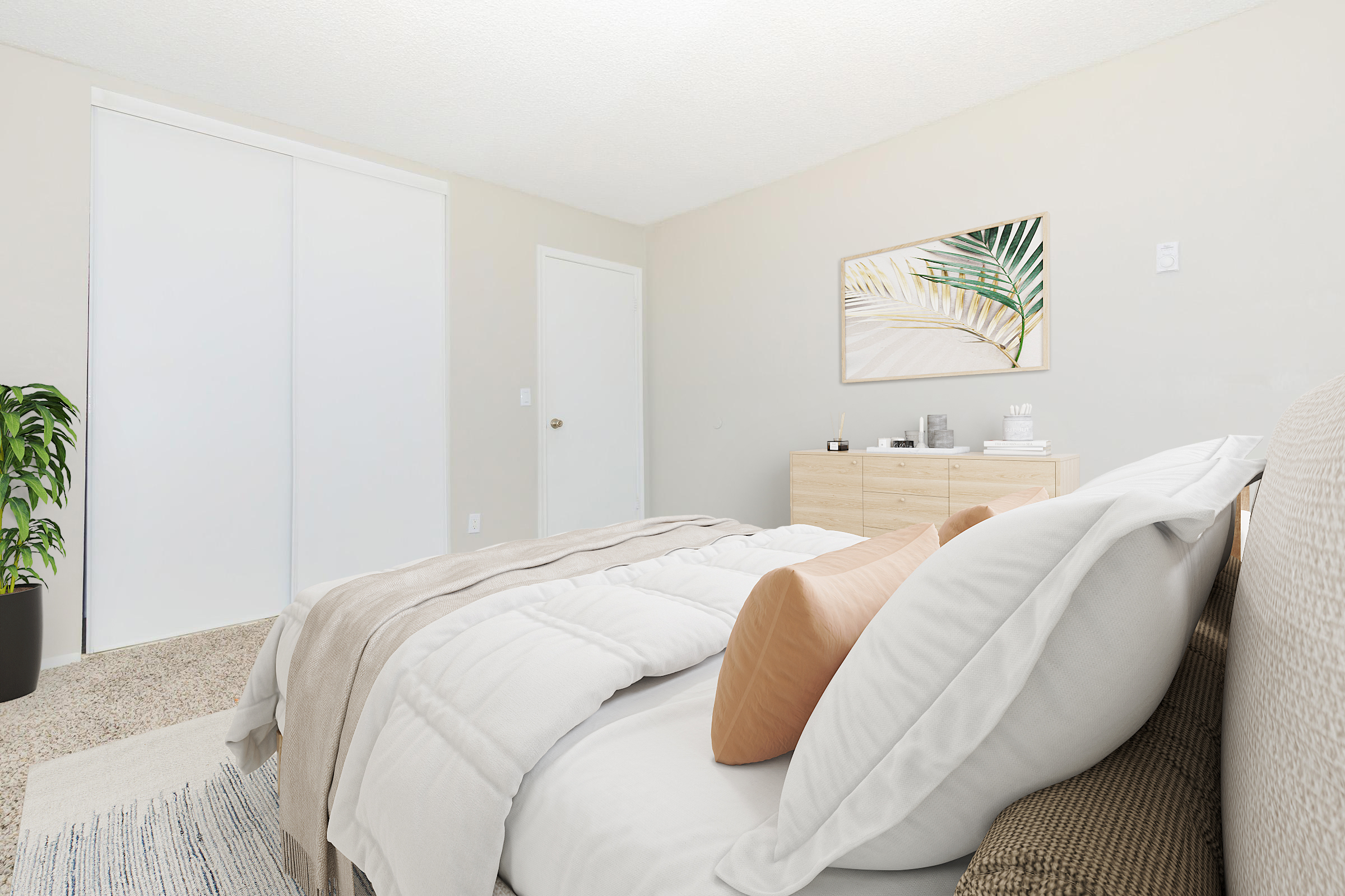 A cozy bedroom featuring a neatly made bed with white bedding and decorative pillows. A light-colored dresser is against the wall, with minimal decor. There is a large closet with sliding doors and a potted plant in the corner, enhancing the serene atmosphere of the room. Bright, natural light illuminates the space.