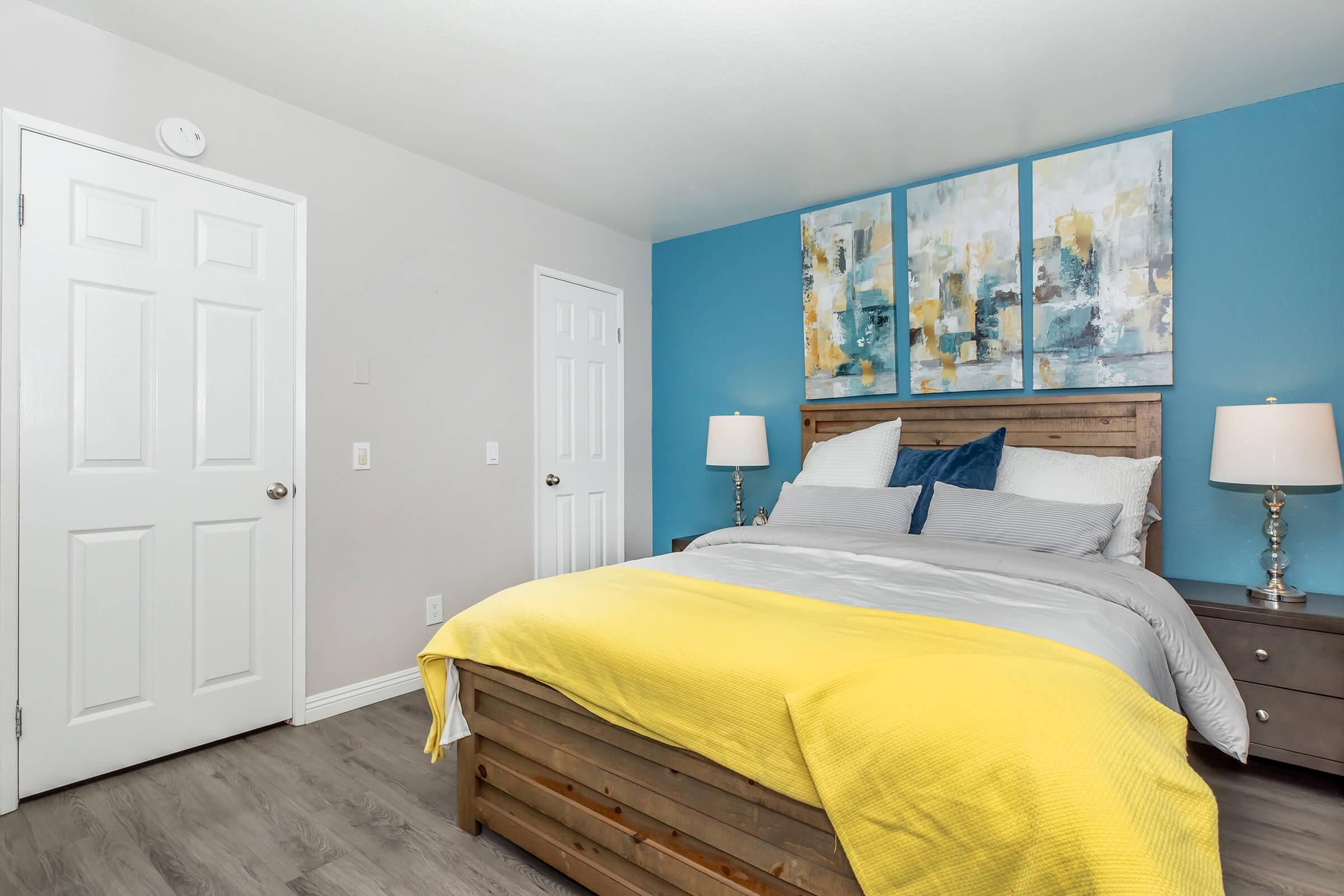 1 Bedroom Apartments in Redlands CA - Parkview Terrace - A Modern Bedroom with Wood-Like Flooring, Large Bed, With Two-Tone Walls and White Doors