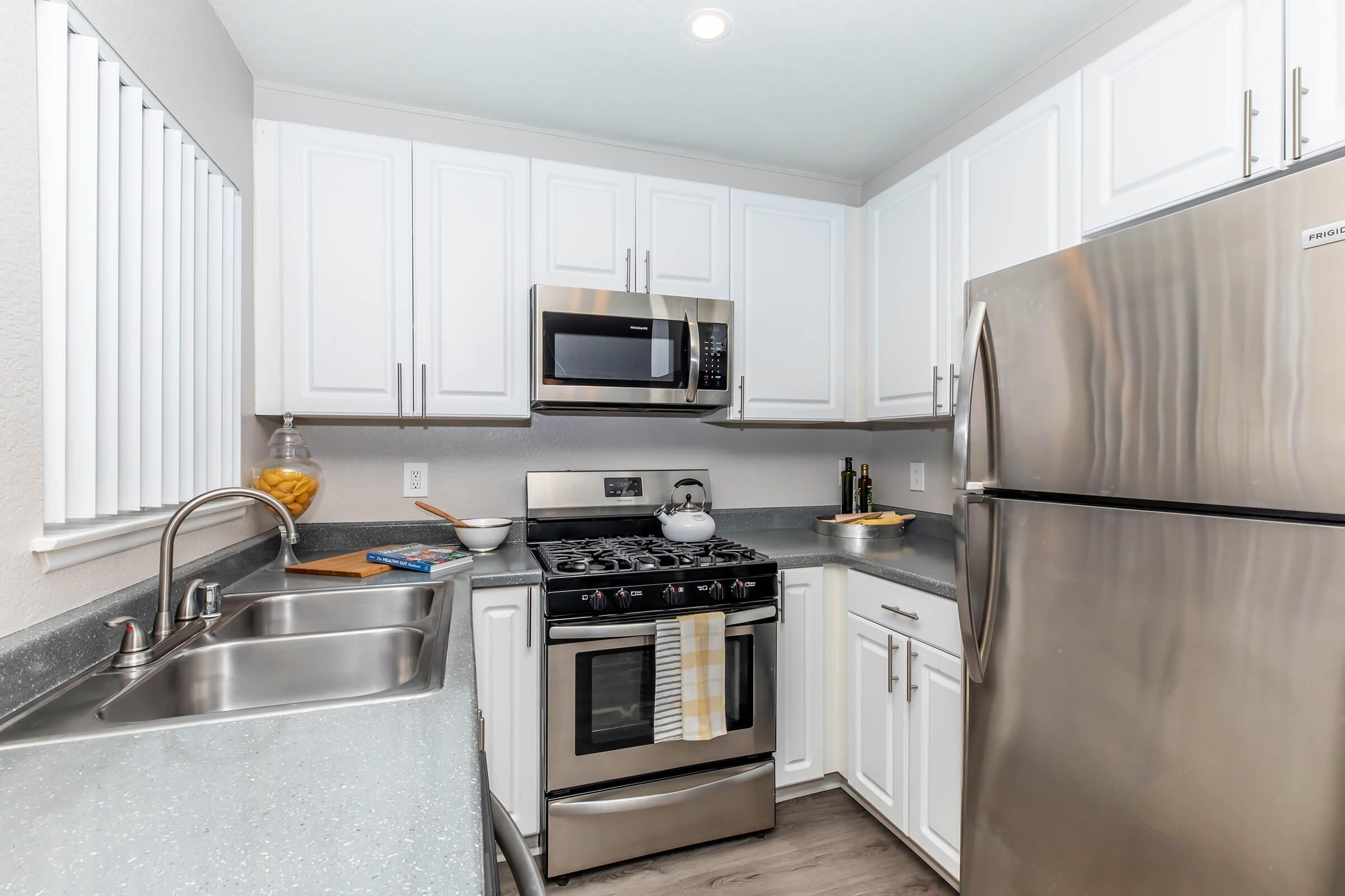 2 Bedroom Apartments in Redlands CA - Parkview Terrace - Kitchen with Stainless Steel Appliances, White Cabinetry, Double Sink, Wood-Like Flooring, and Overhead Lighting