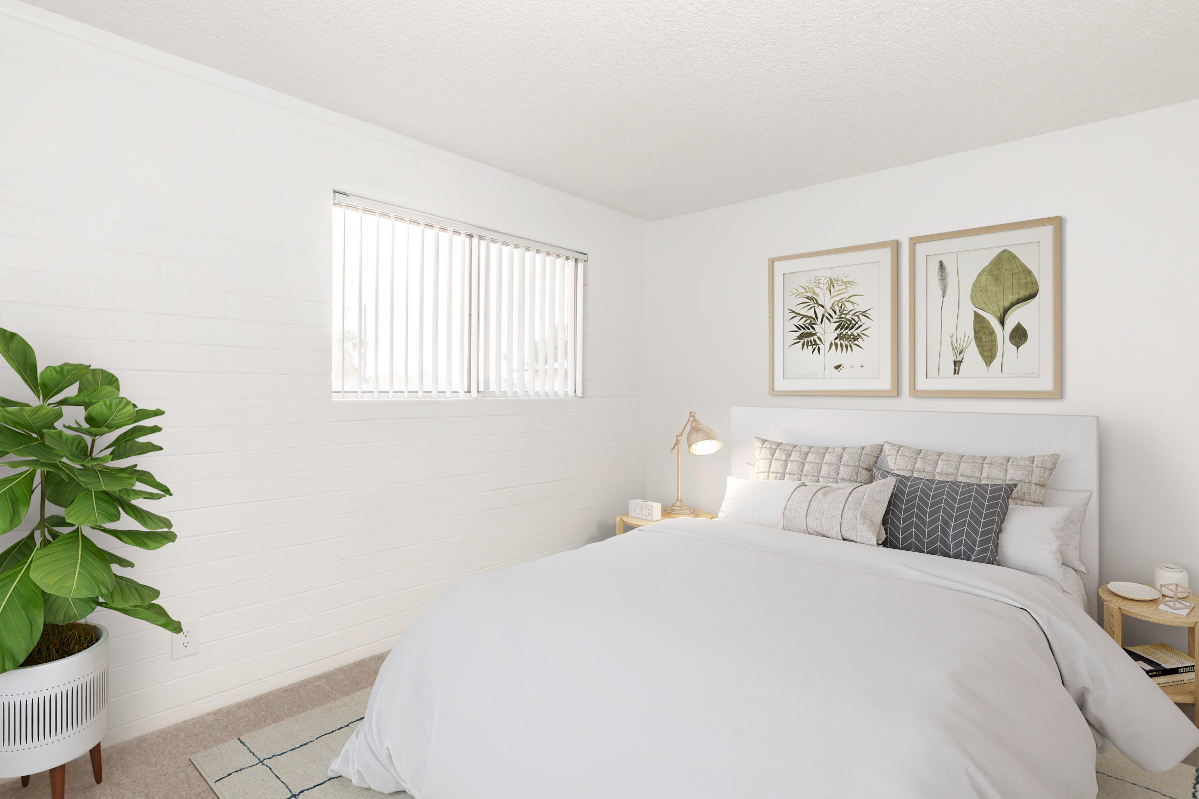 A cozy bedroom featuring a light gray bed with multiple pillows, two framed botanical prints on the wall, a bedside table with a lamp, and a large green plant in a white pot. The walls are painted white, and there is a window with vertical blinds allowing natural light into the space.