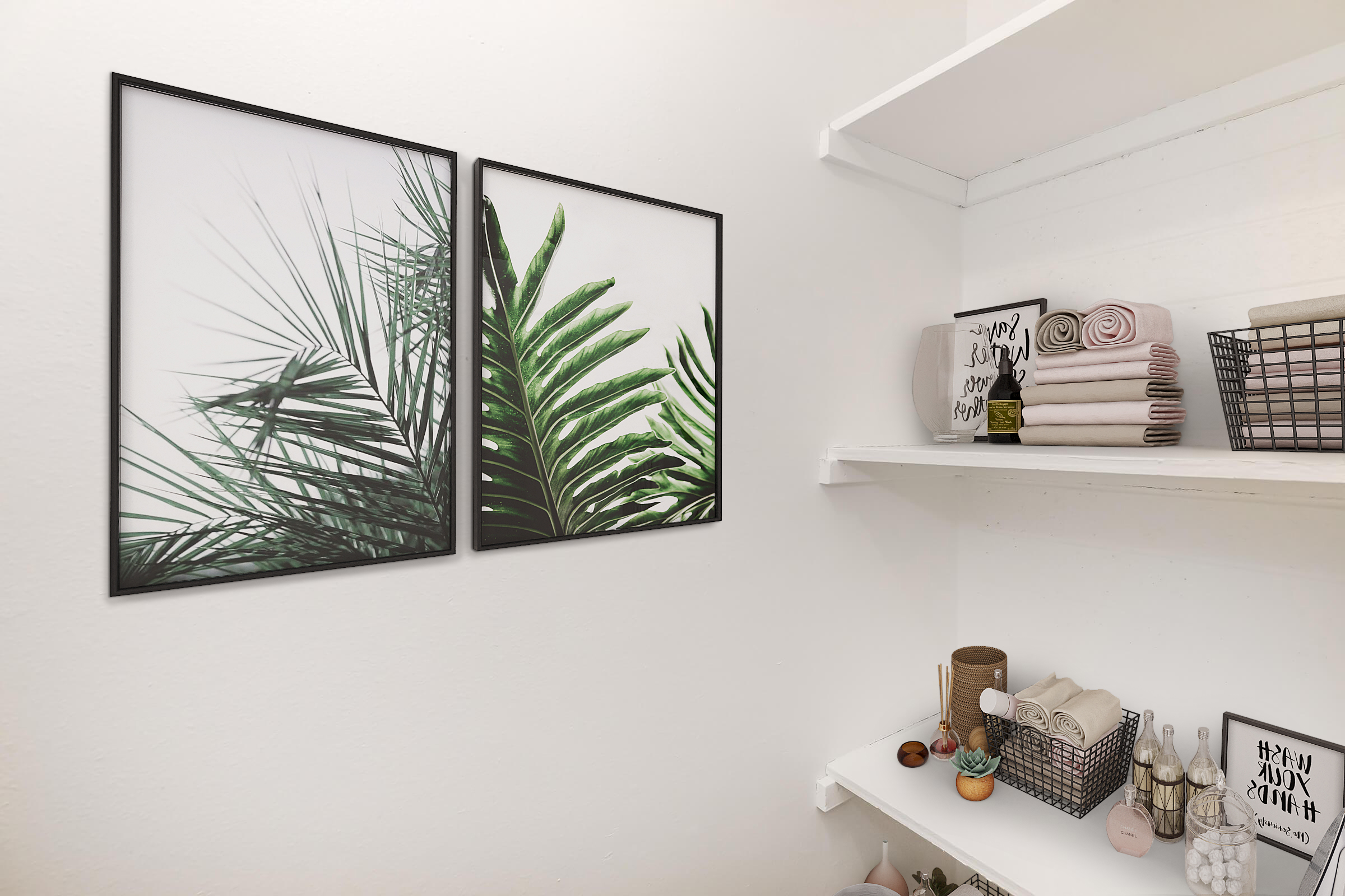 A corner of a room featuring two framed botanical prints of palm leaves on the wall. Below, there are white shelves displaying neatly arranged towels, decorative items, and small baskets. The overall decor is minimalist and modern, creating a calming atmosphere.