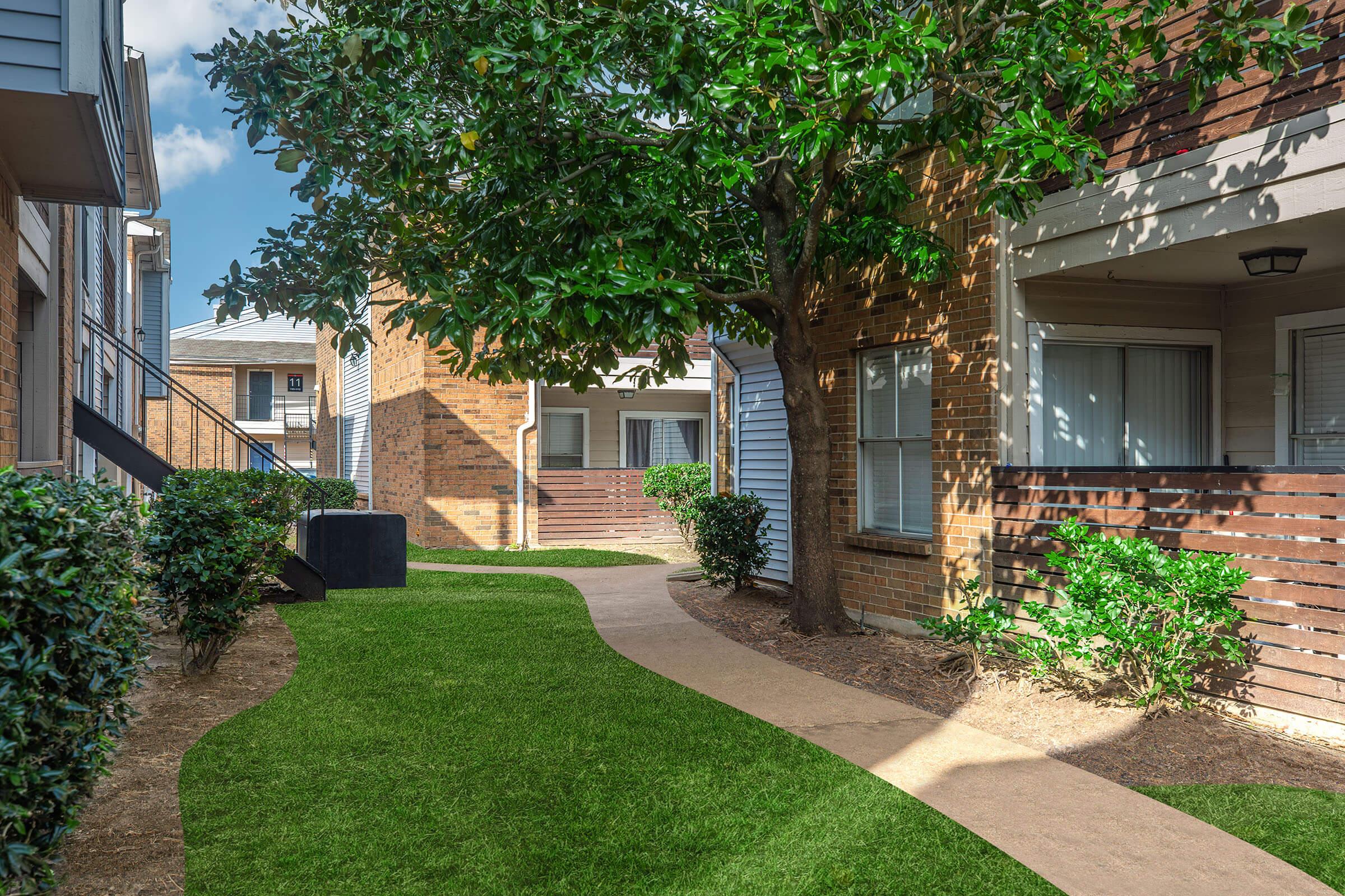 a house with a lawn in front of a brick building