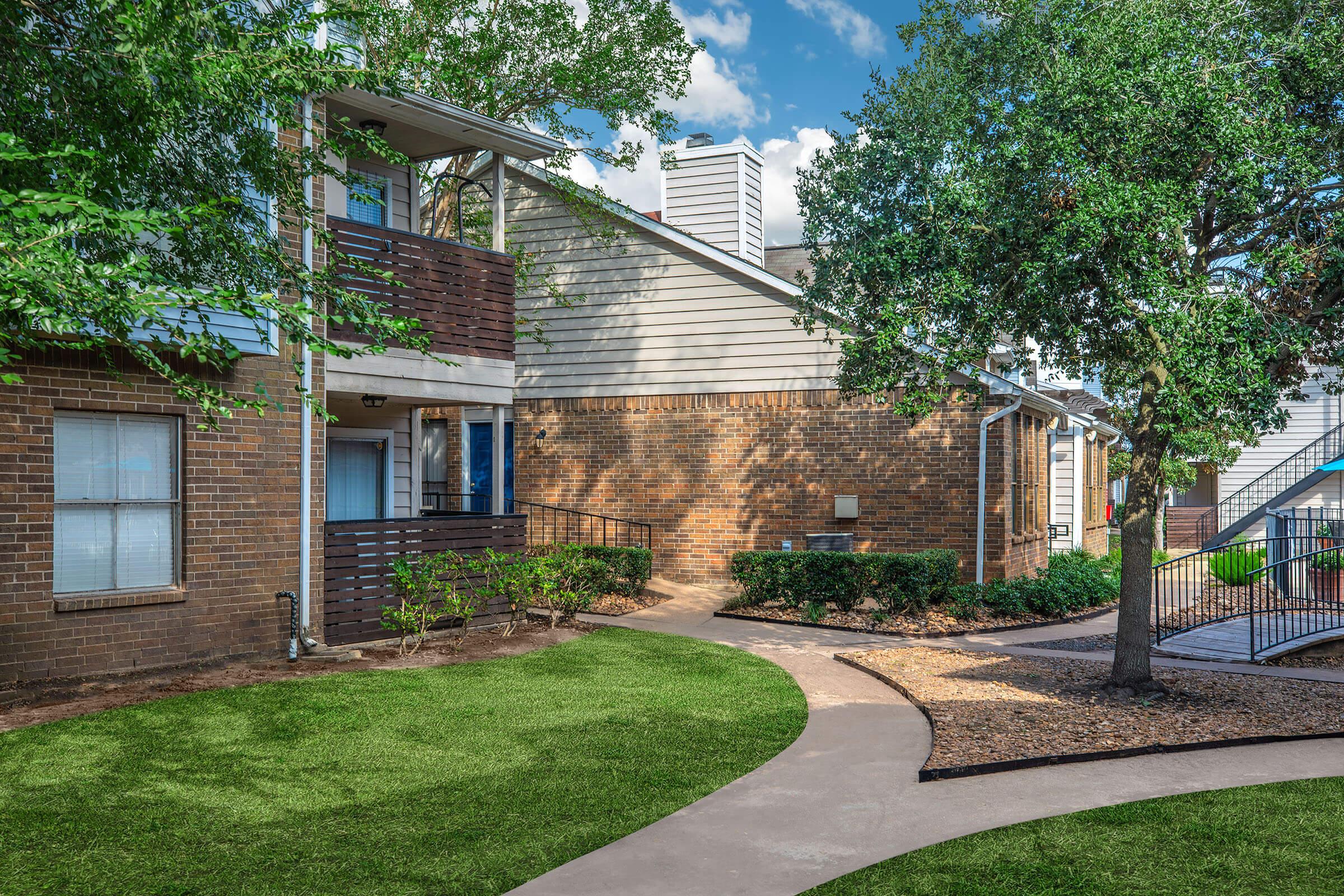 a house with a lawn in front of a brick building