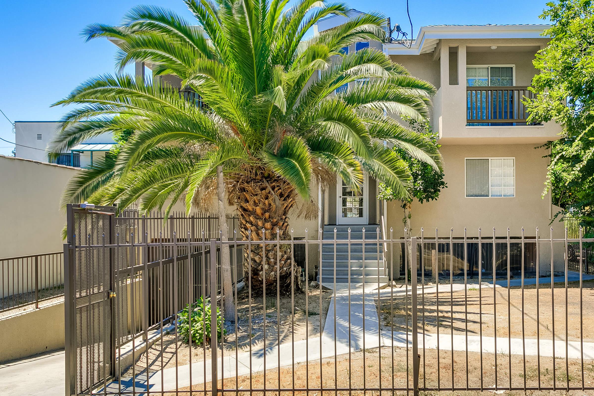 a building with palm trees and a fence