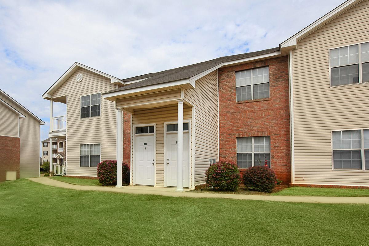 a large brick building with grass in front of a house