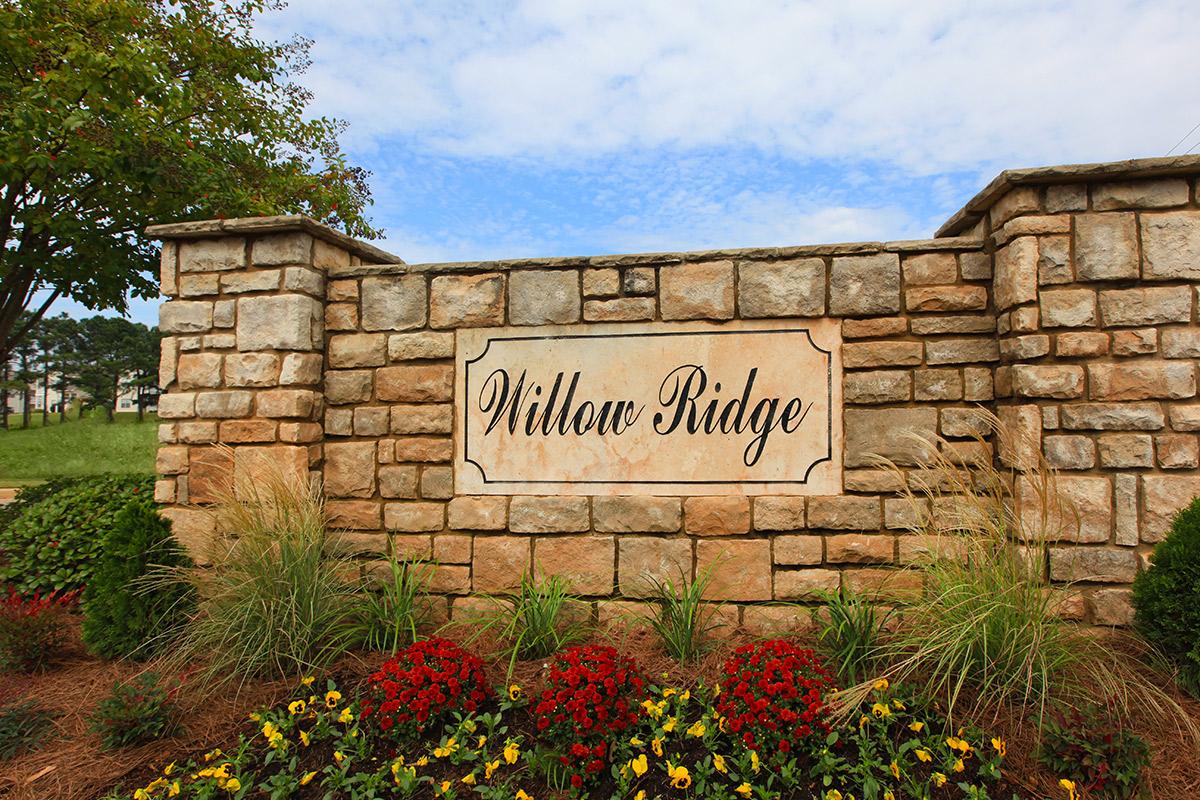 a stone sign in front of a brick wall