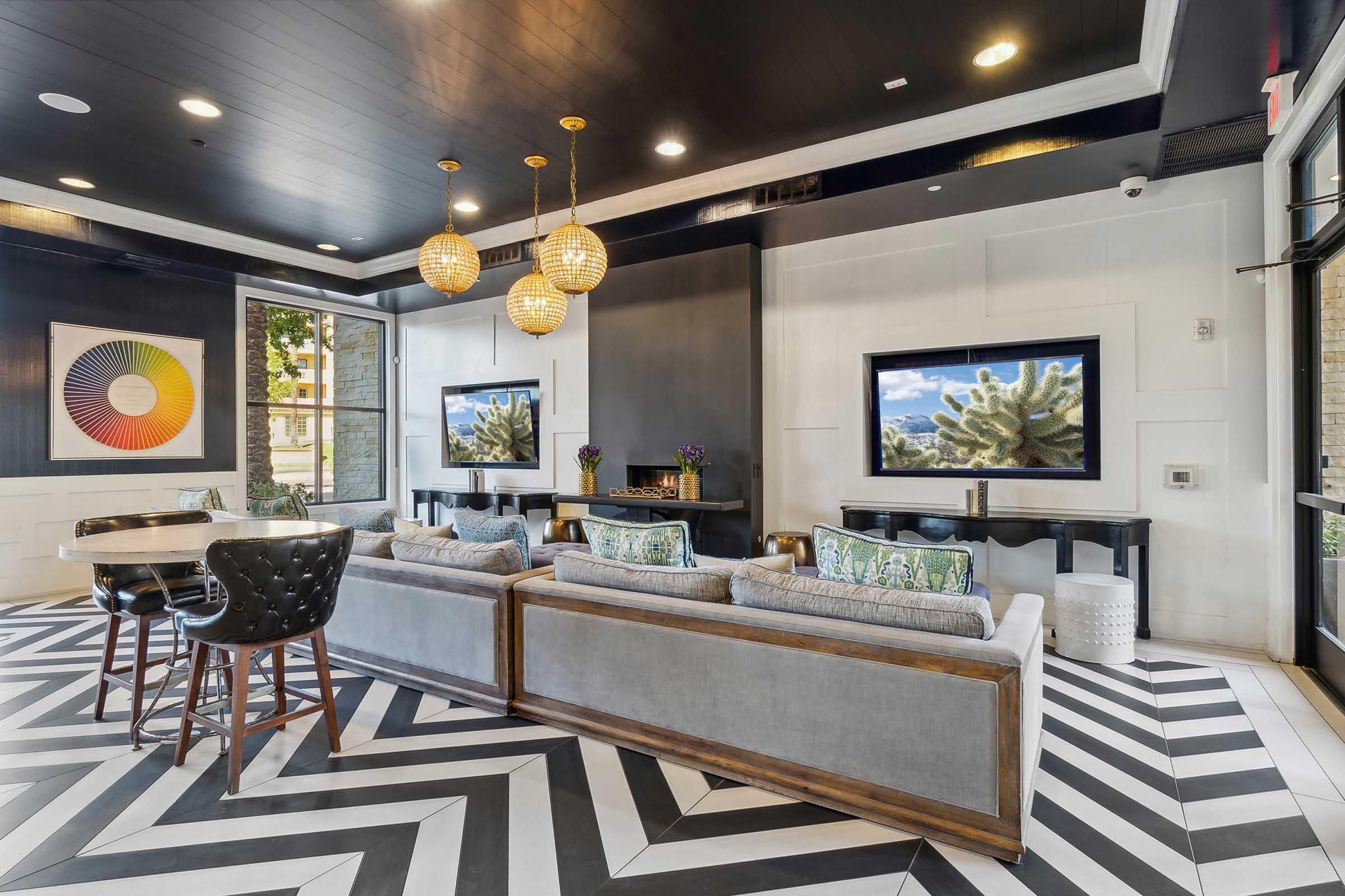 Modern lobby interior with a chevron-patterned floor, featuring a seating area with gray couches and decorative pillows.