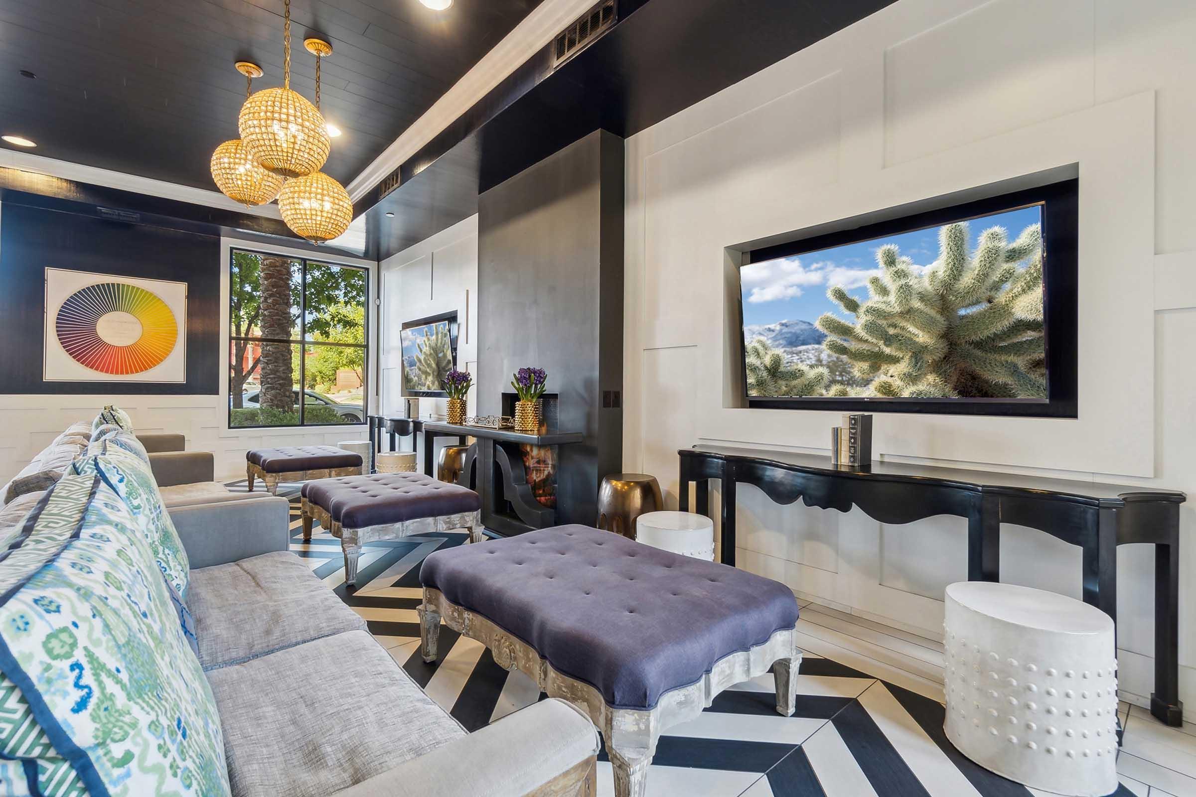A modern living room featuring stylish seating with colorful cushions, a large flat-screen TV displaying a nature scene, and an elegant black console table.