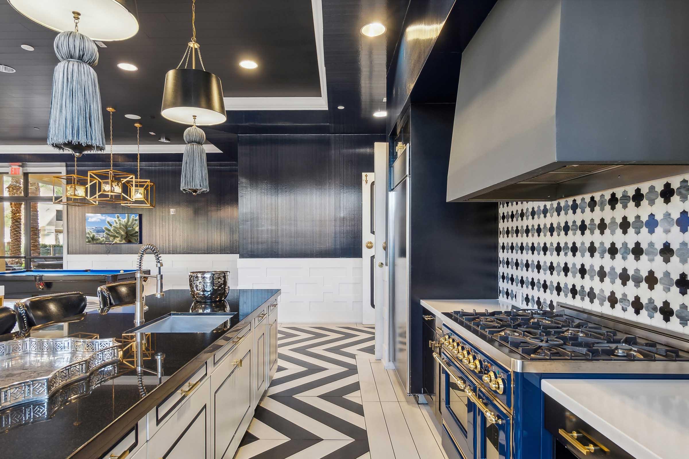 Modern kitchen featuring a sleek black and white color scheme, decorative light fixtures with tassels, a stainless steel range hood, and a stylish tile backsplash.