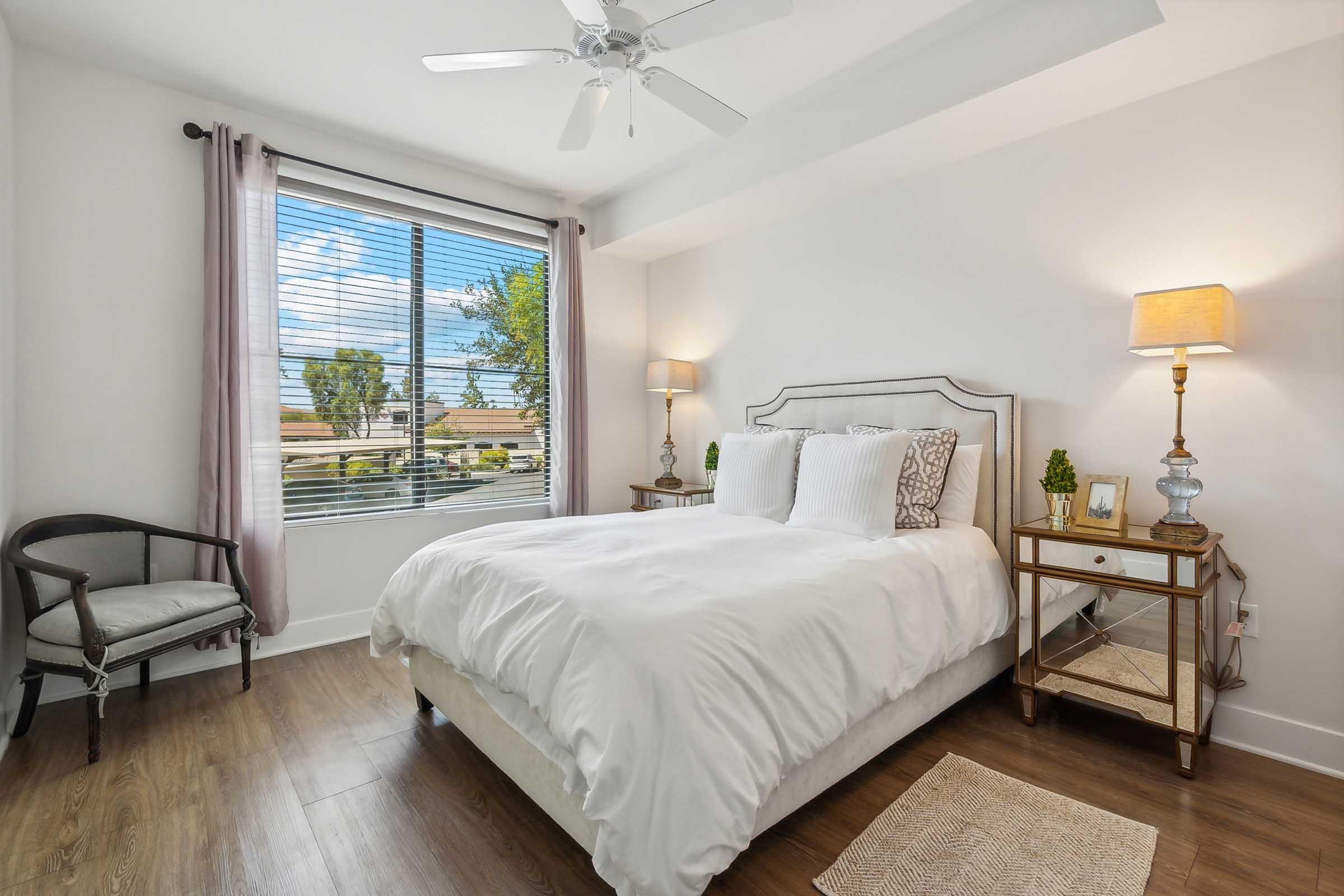 A bright and airy bedroom featuring a cozy bed with white bedding, a pair of decorative pillows, and a stylish headboard.