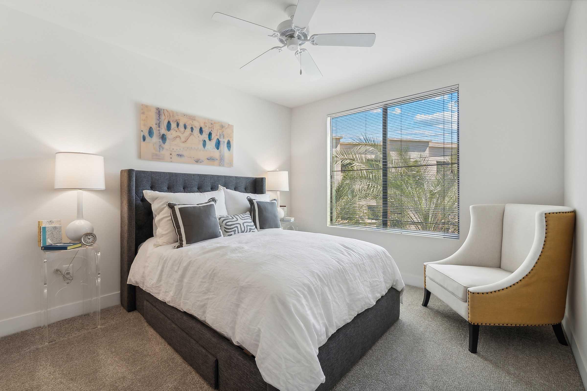 Cozy bedroom featuring a queen-sized bed with a gray upholstered headboard, white bedding, and decorative pillows.