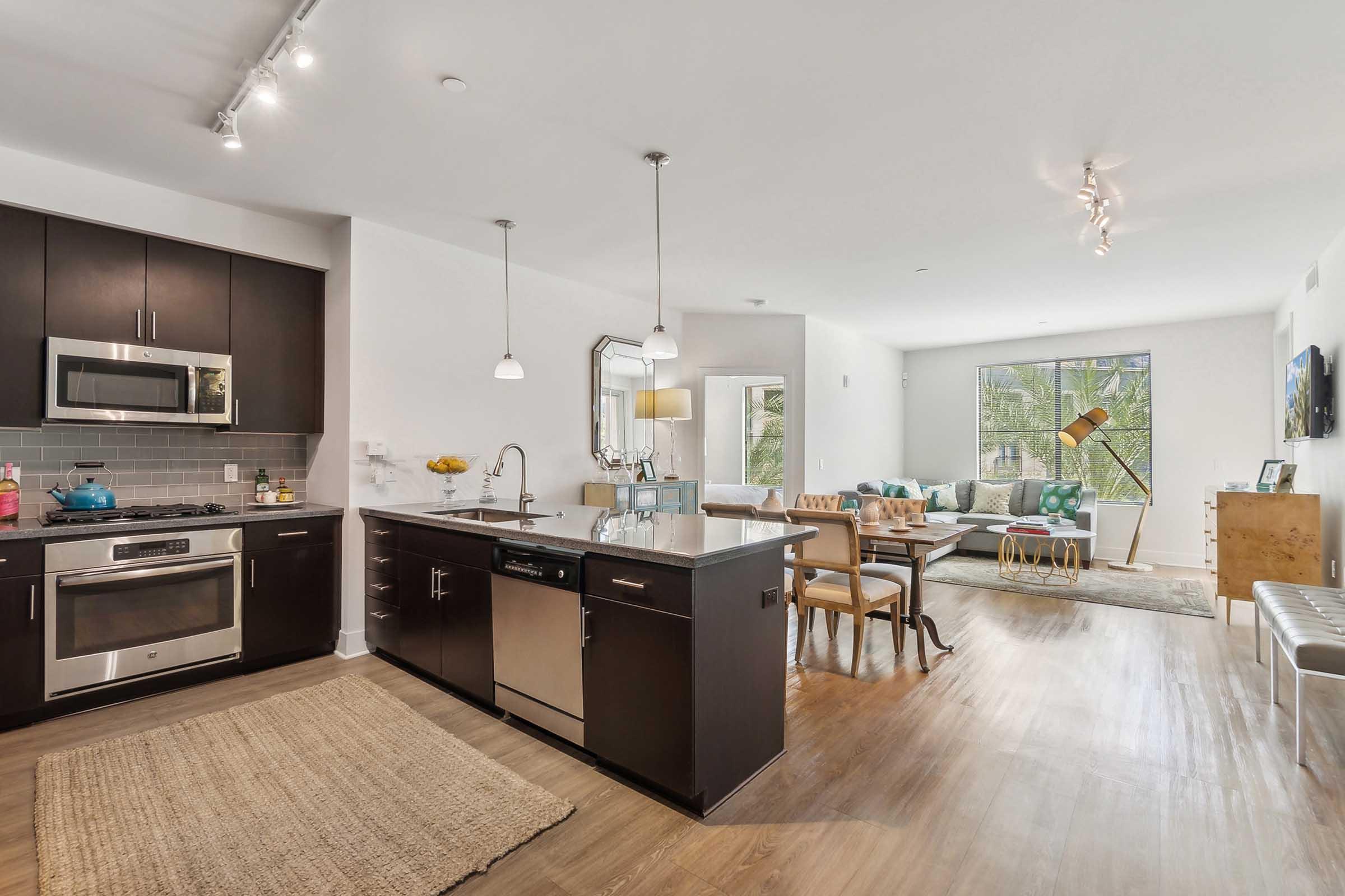 Modern kitchen with dark cabinetry and stainless steel appliances, featuring a large island.