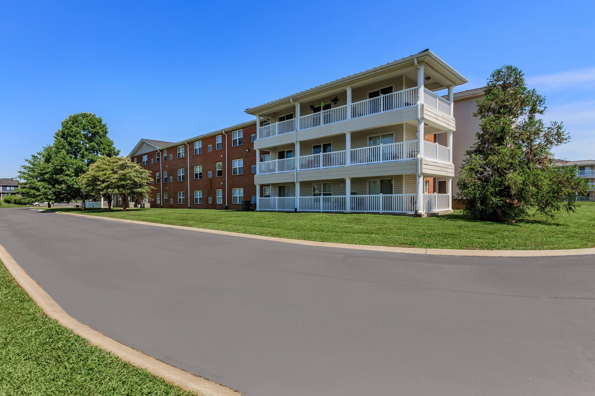 an empty road with grass on the side of a building