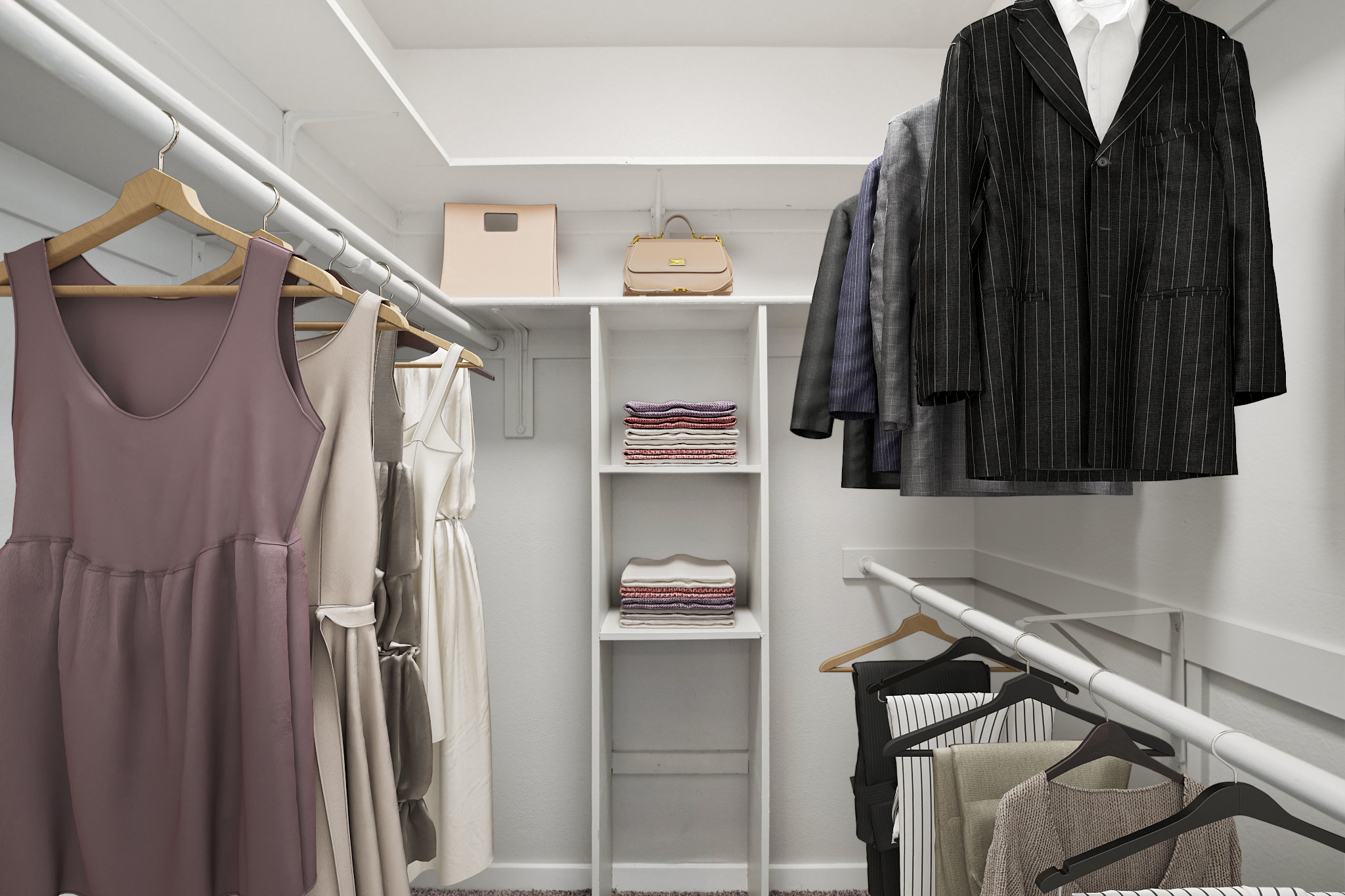 A well-organized closet featuring a variety of clothing items. On the left, there are hanging dresses in soft colors, while on the right, multiple suits hang on hangers. A shelf in the center displays neatly folded clothing items, with a small handbag placed on top. The walls are painted white, creating a clean and bright atmosphere.