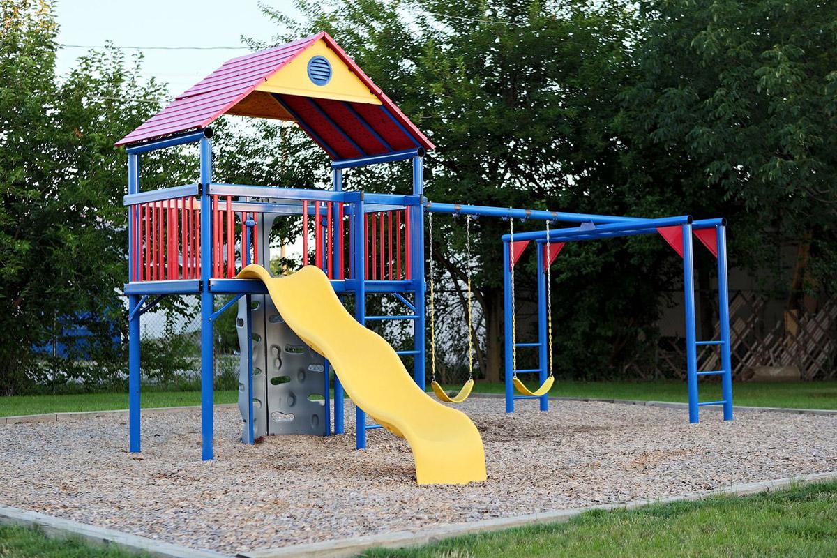 a playground with a blue umbrella