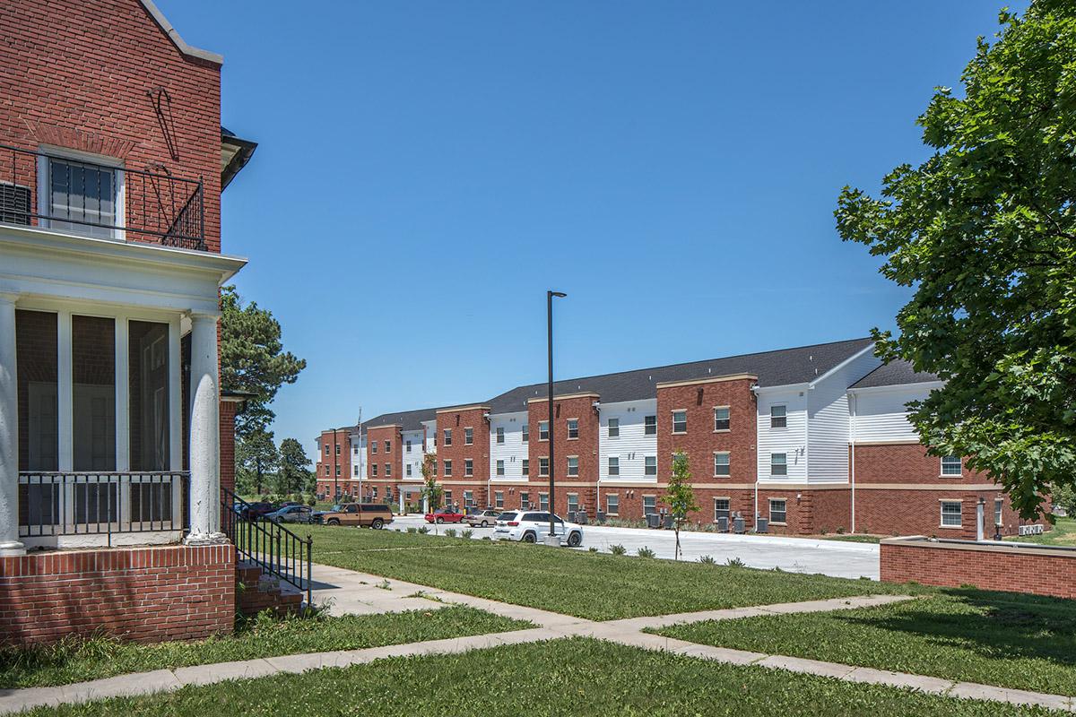 a large brick building with grass in front of a house