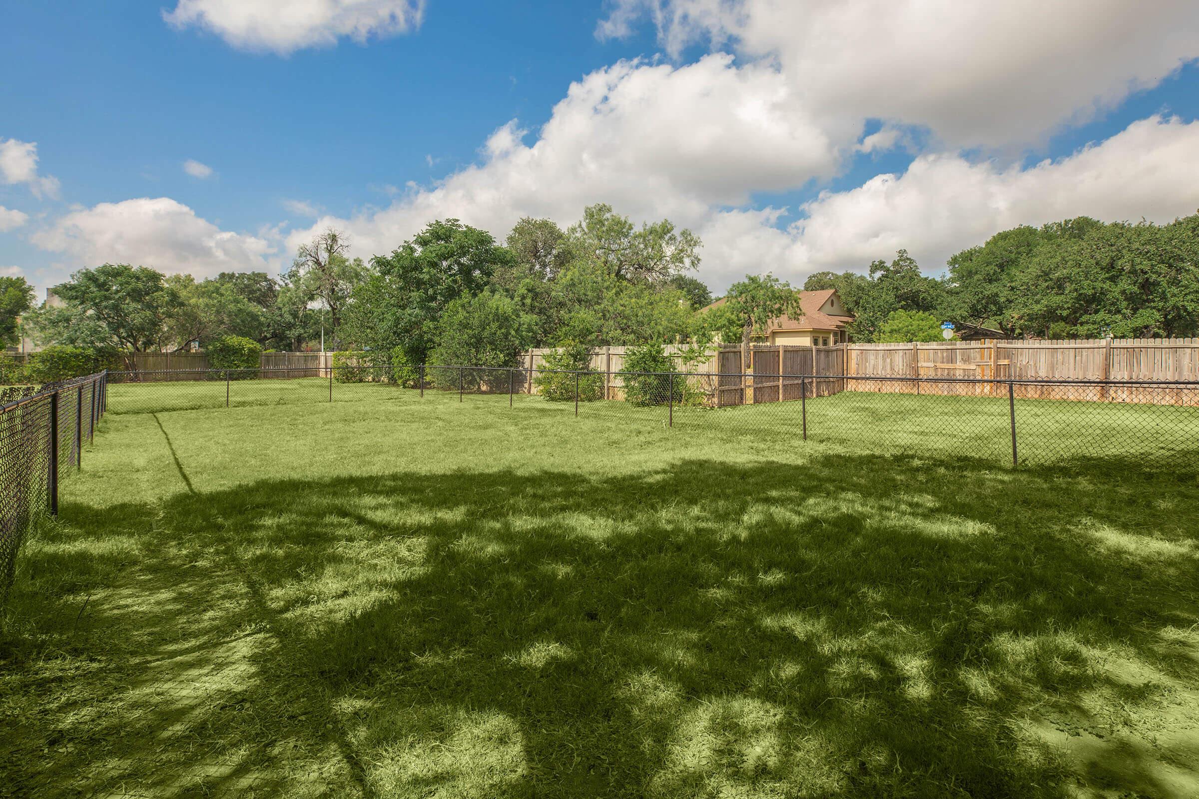 a large green field with trees in the background