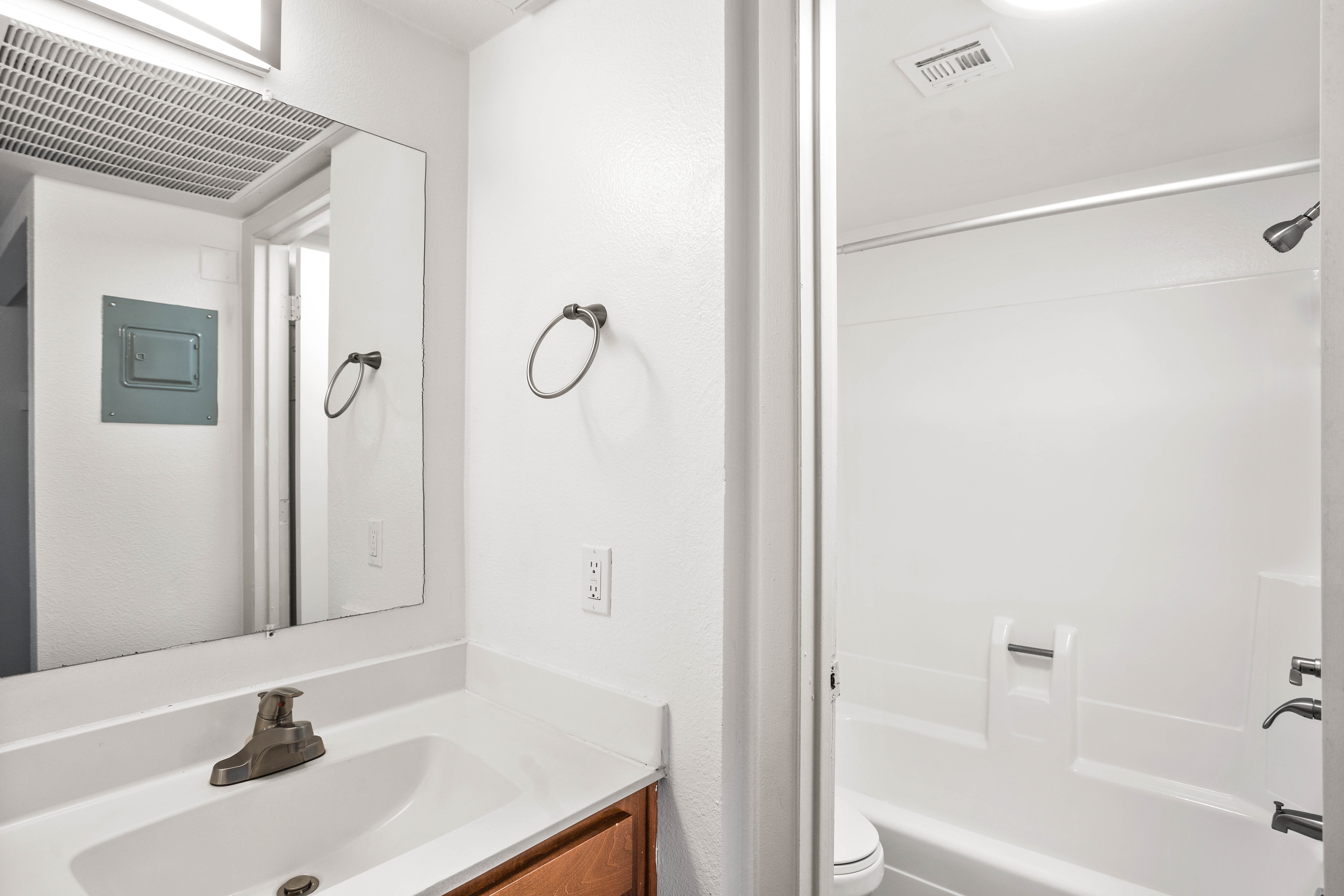 Clean bathroom with cherry wood cabinets, a large mirror, and separate toilet and shower room