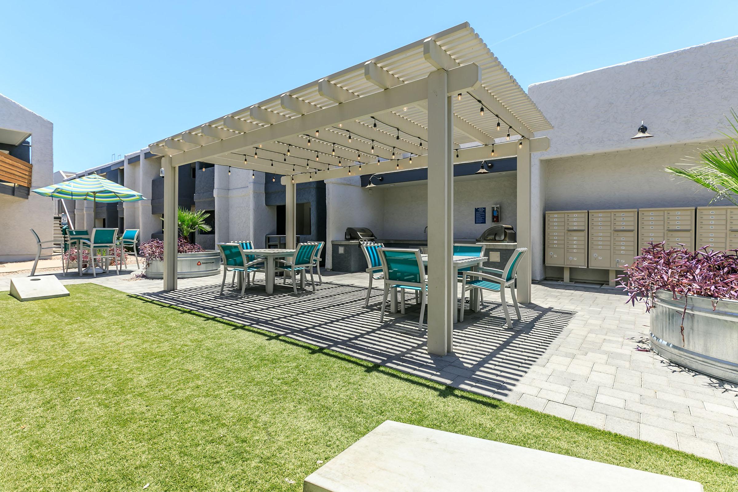 Shaded outdoor pergola with overhead bulb lights and patio tables