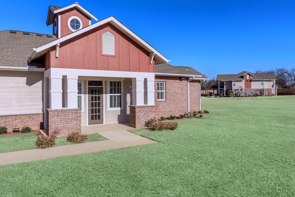a house with a lawn in front of a brick building