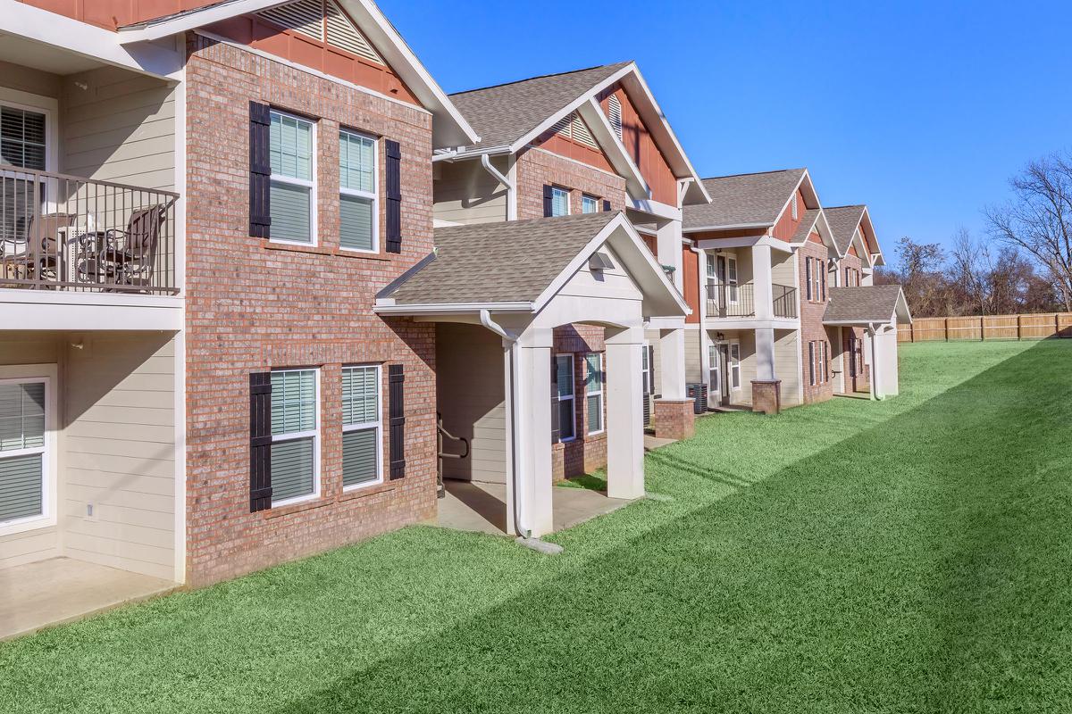 a large brick building with grass in front of a house