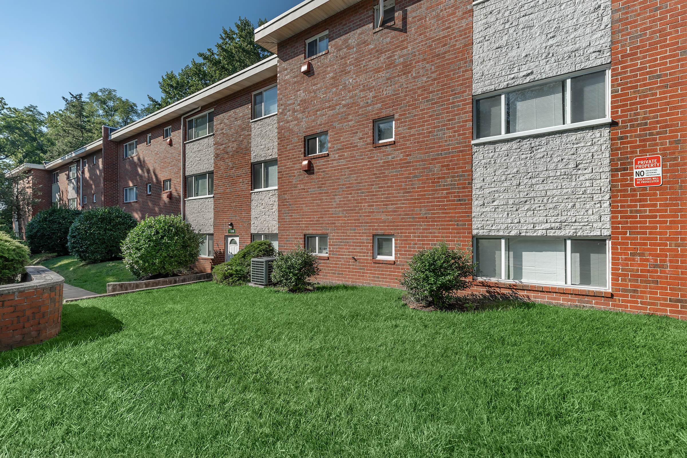 a large brick building with green grass in front of a house