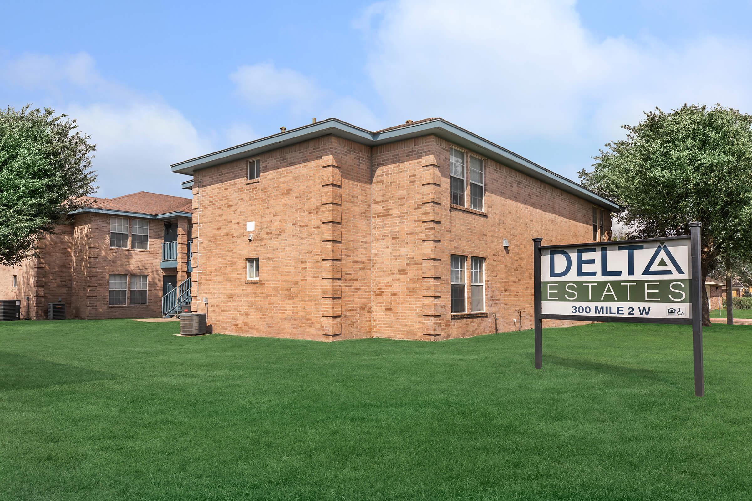 a large brick building with a grassy field