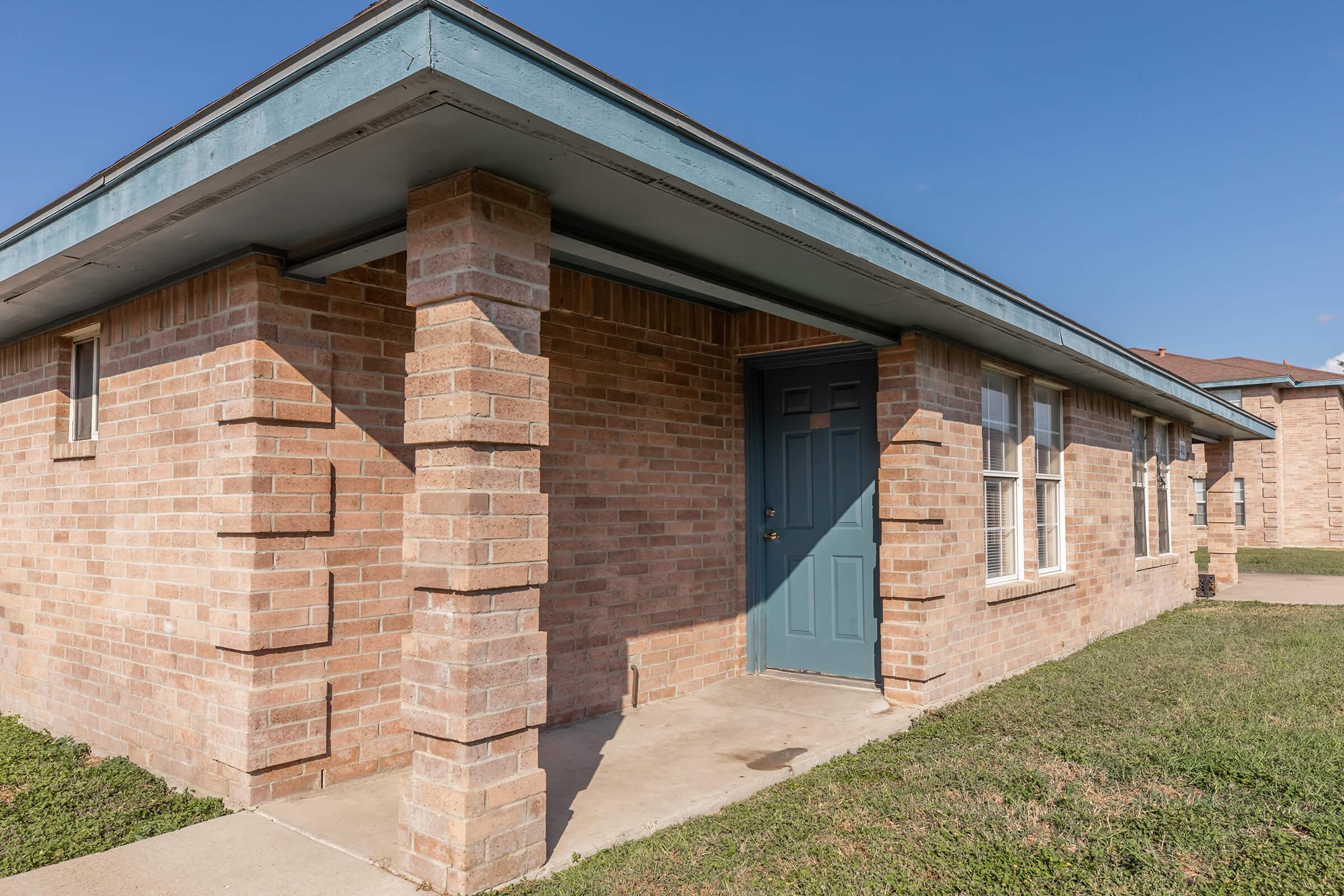 a large brick building with grass in front of a house