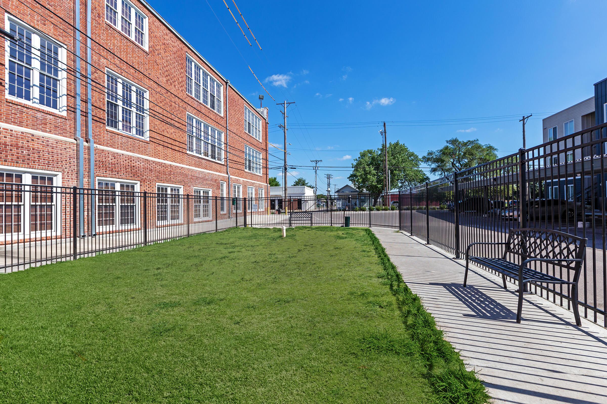 a large brick building with grass and a fence