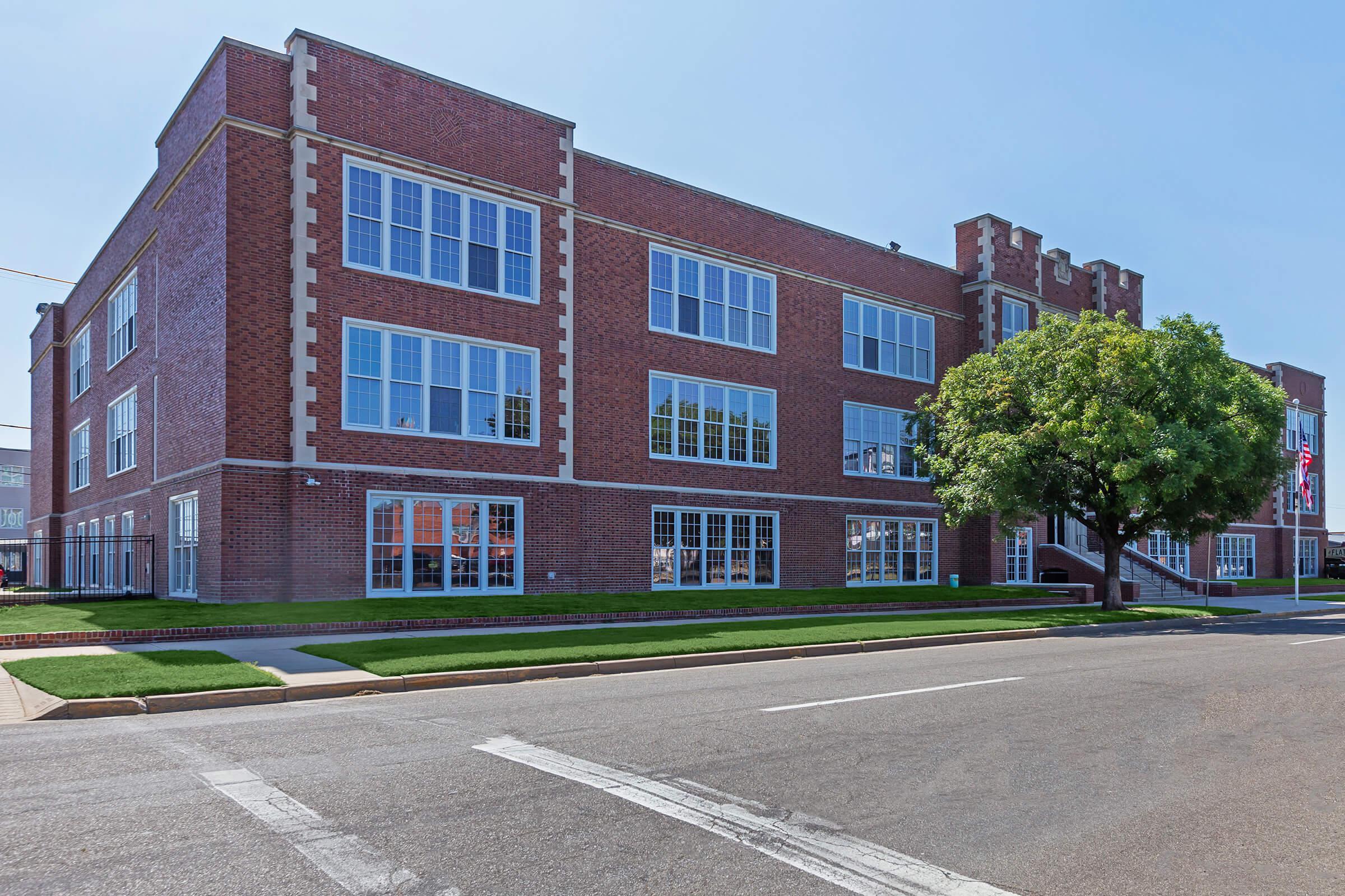 a large brick building with a clock on the side of a road