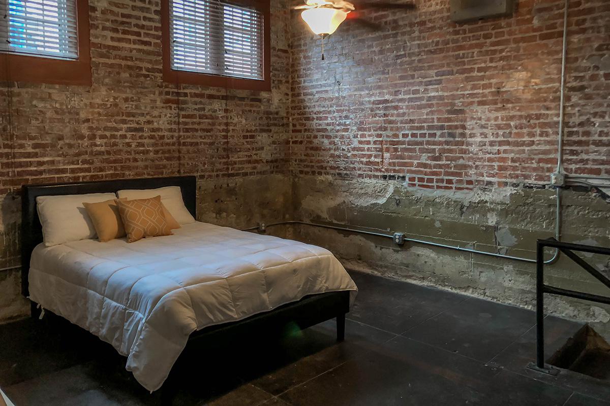 a bedroom with a bed and window in a brick room