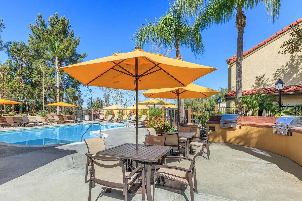 Tables with yellow umbrellas next to the community pool