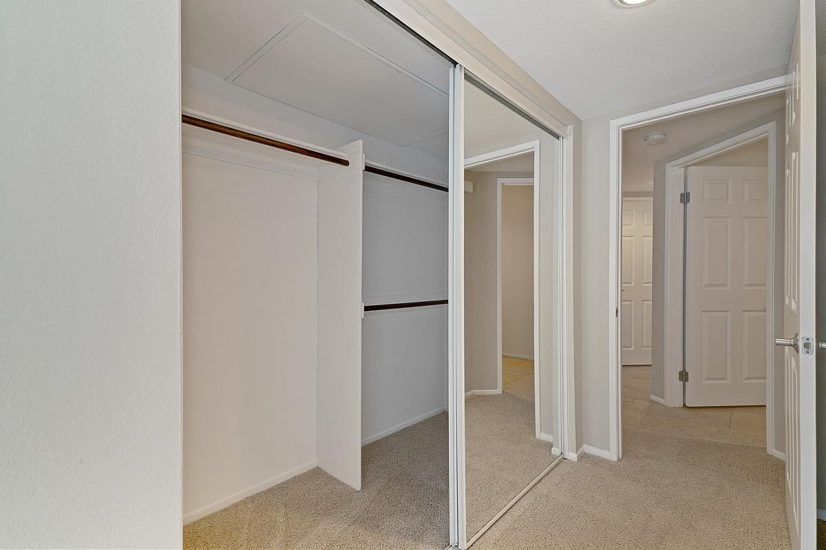 Open bedroom closet with sliding mirror glass doors