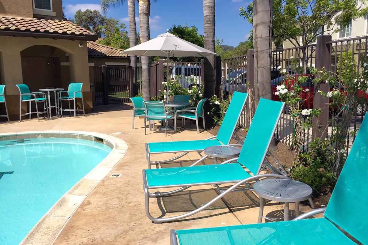 a group of lawn chairs sitting on top of a blue pool