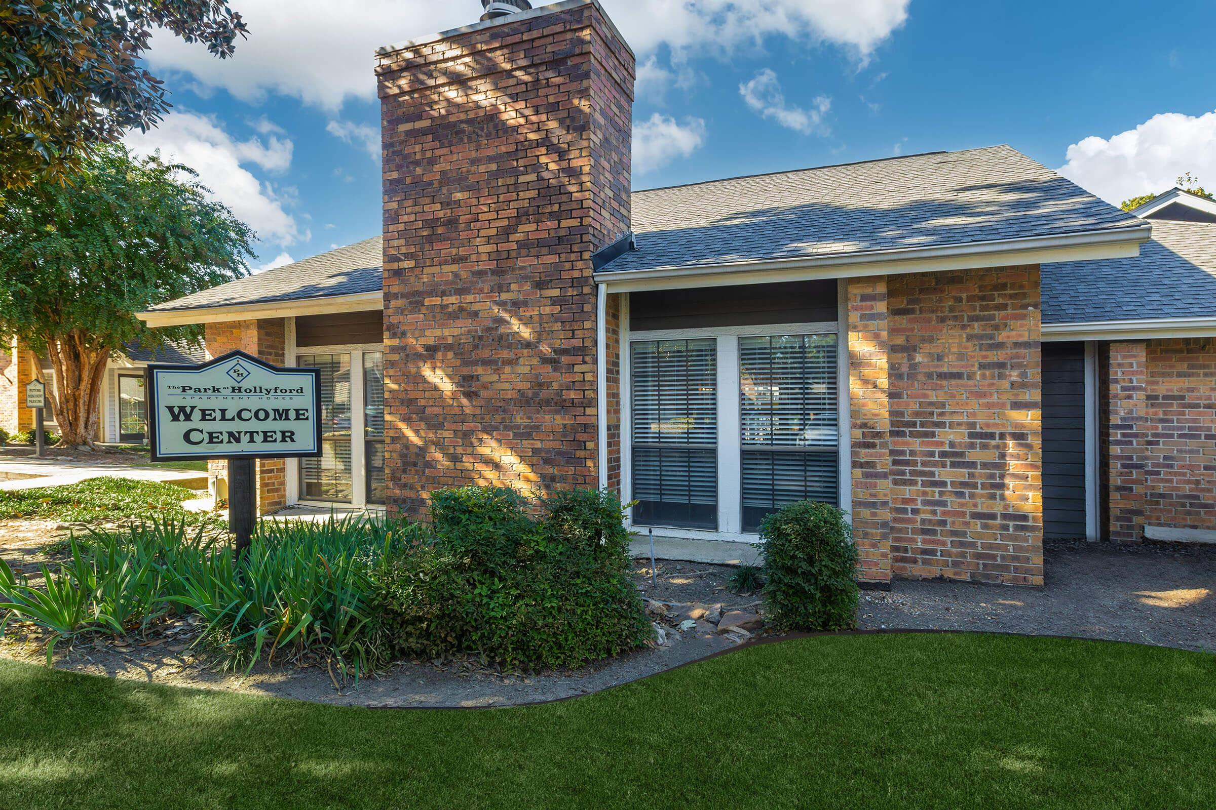 a large brick building with grass in front of a house