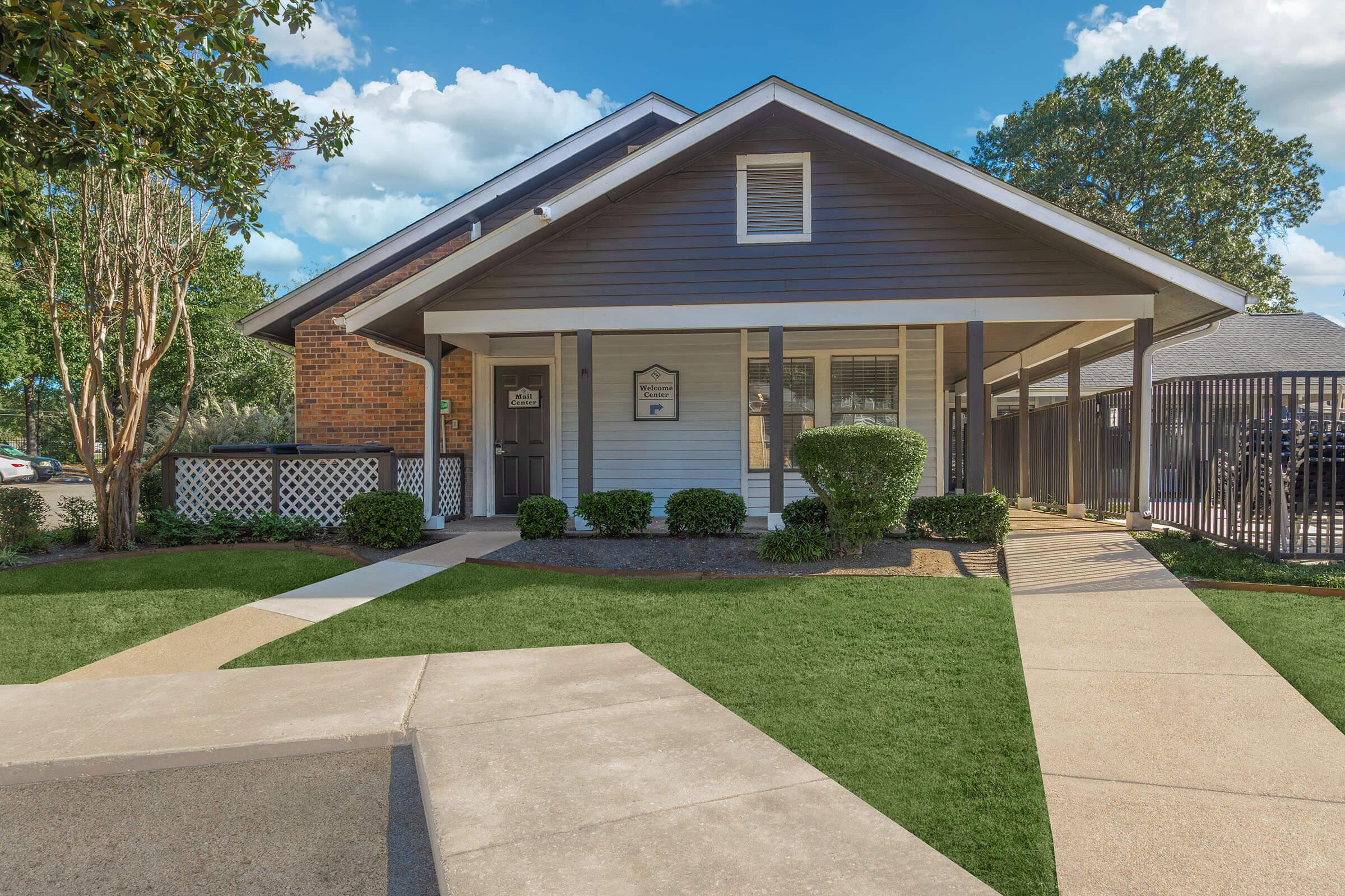 a house with a lawn in front of a brick building