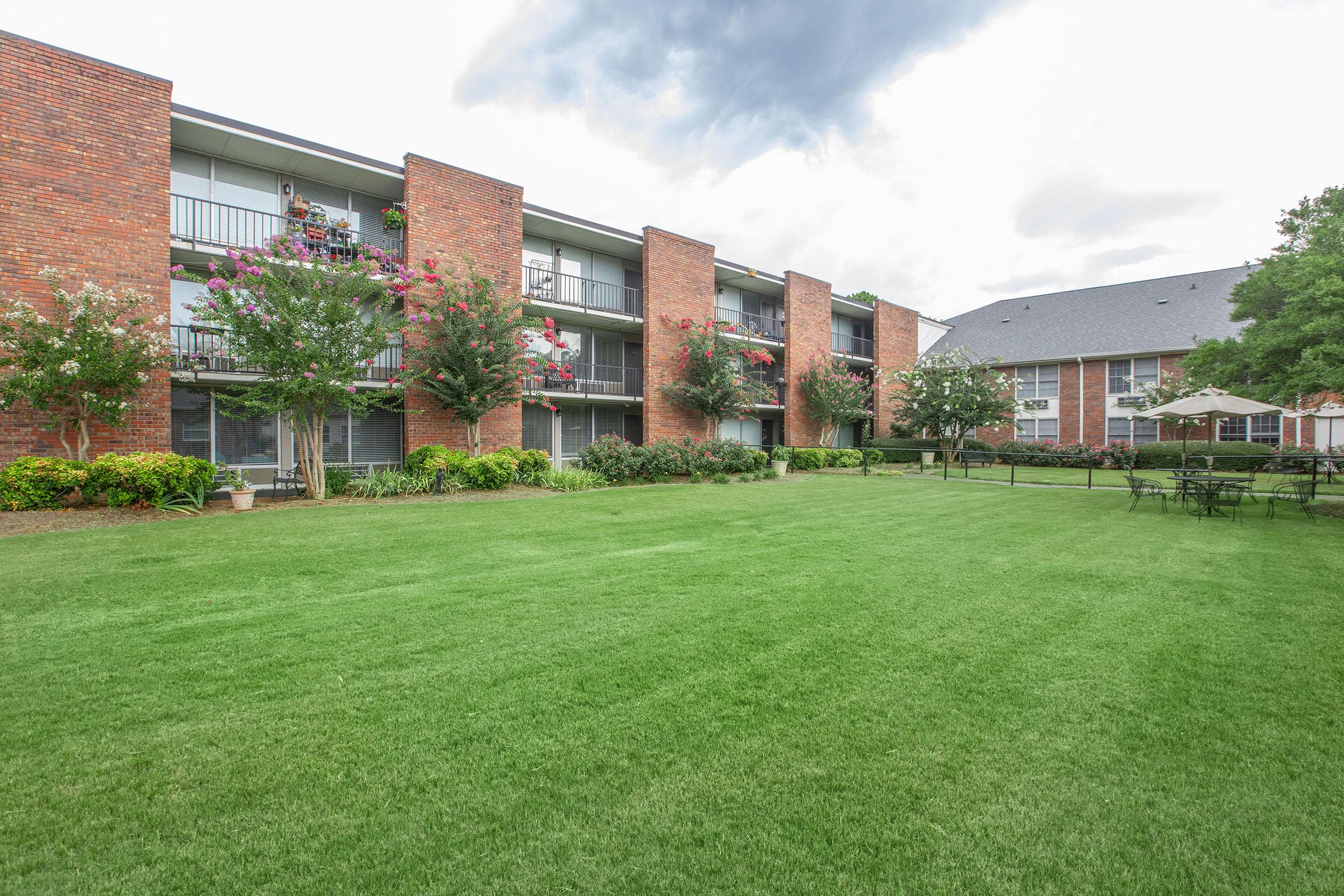 a large brick building with a grassy field