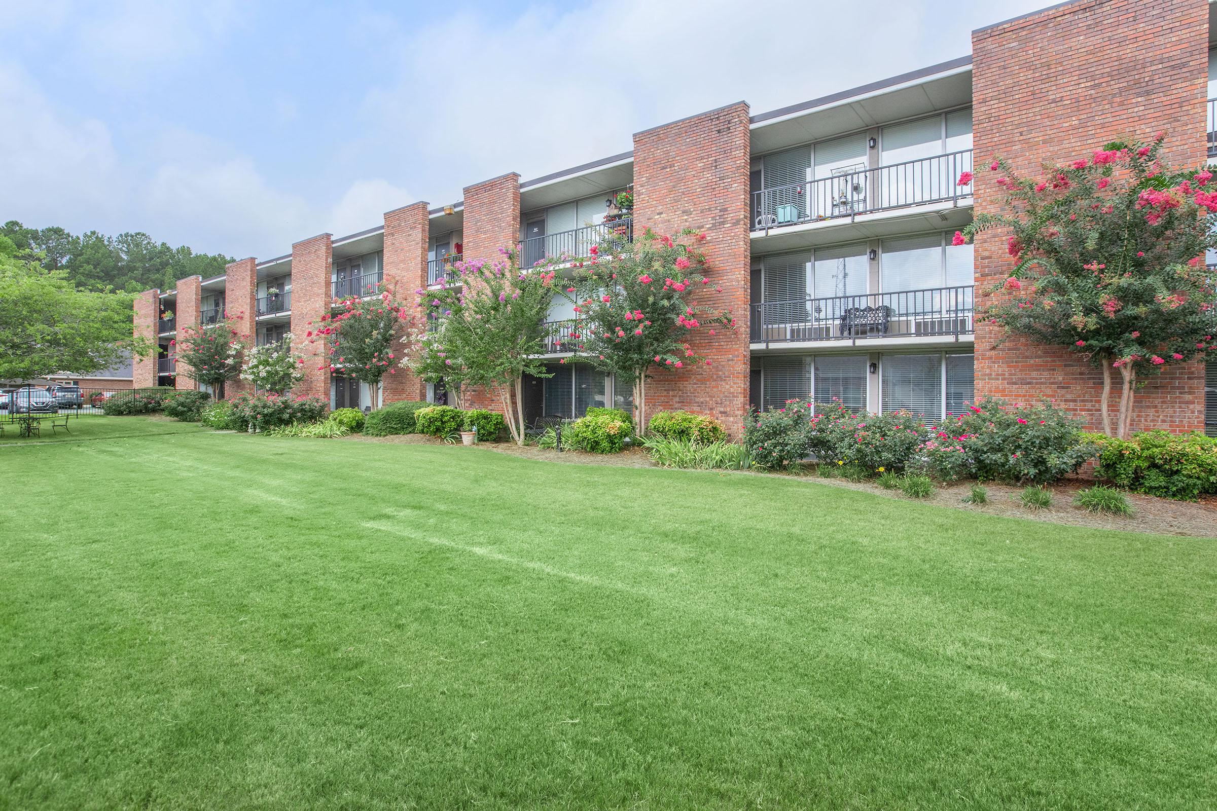 a large brick building with green grass