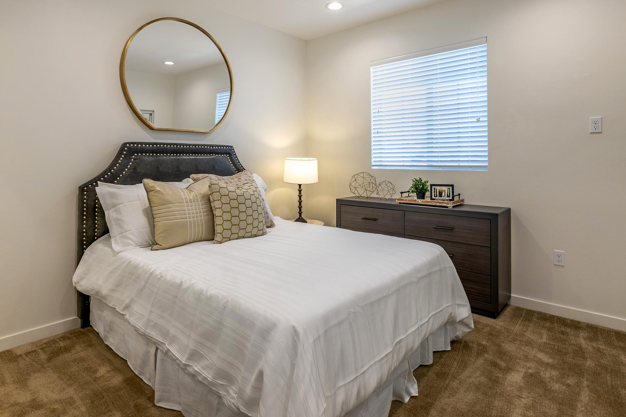 a bedroom with a large bed and round mirror