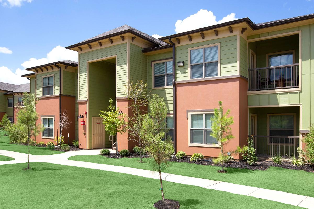 a house with a lawn in front of a brick building