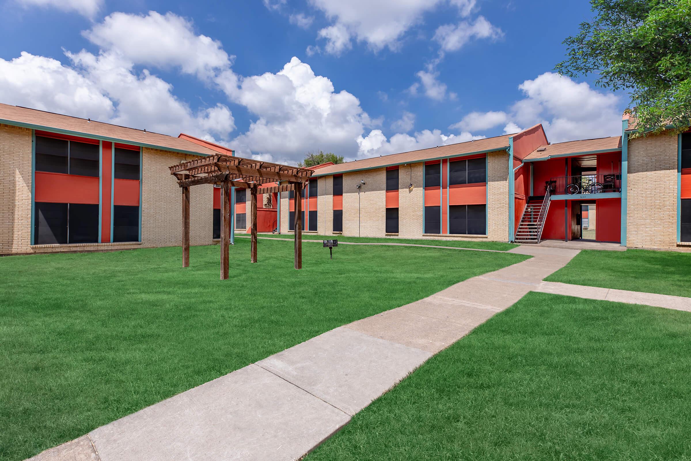 a large brick building with a grassy field