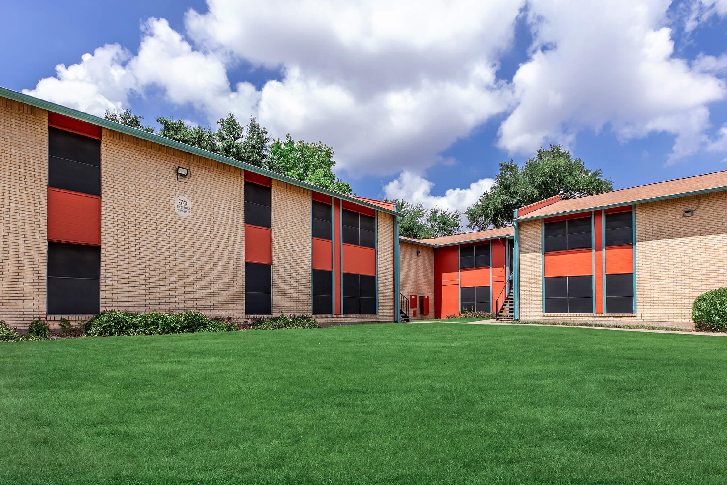 a large brick building with green grass in front of a house