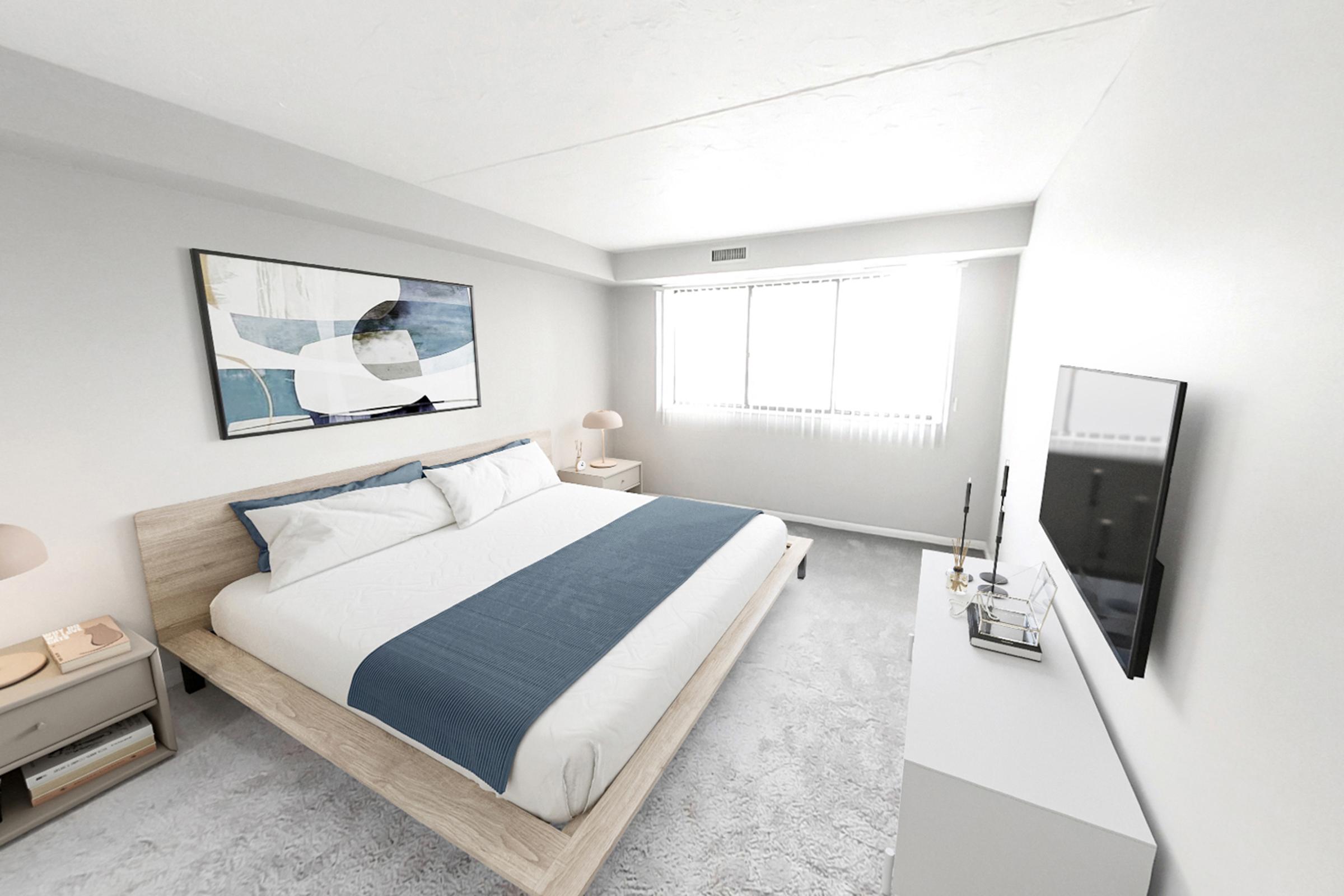 A modern, minimalistic bedroom featuring a large bed with white linens and a blue throw blanket. There is a wooden bed frame, a white dresser, and a wall-mounted TV. Soft lighting from bedside lamps illuminates the space. A large window allows natural light to enter, with light gray walls and carpet providing a calming atmosphere.