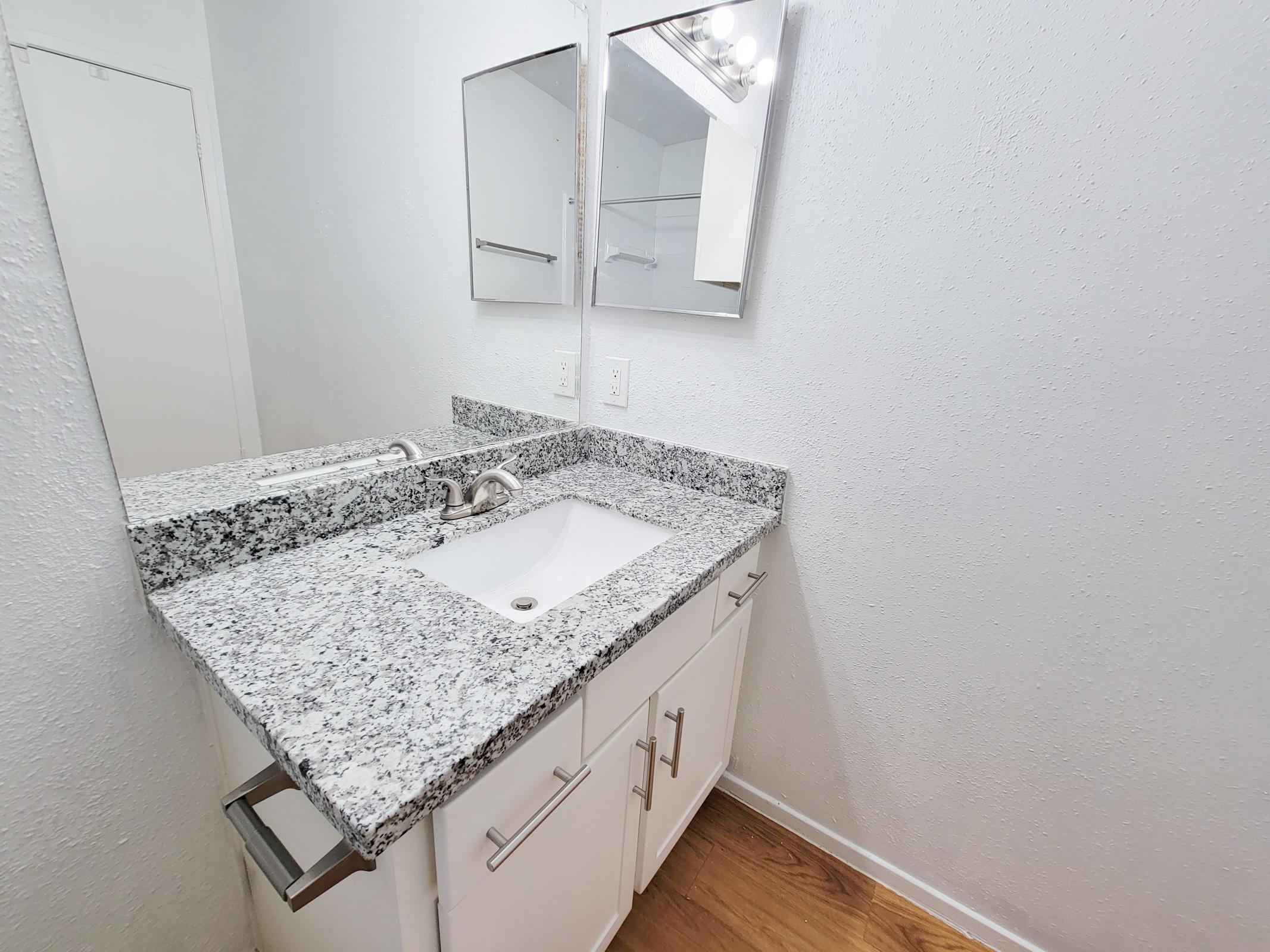 a bedroom area with a sink and a mirror