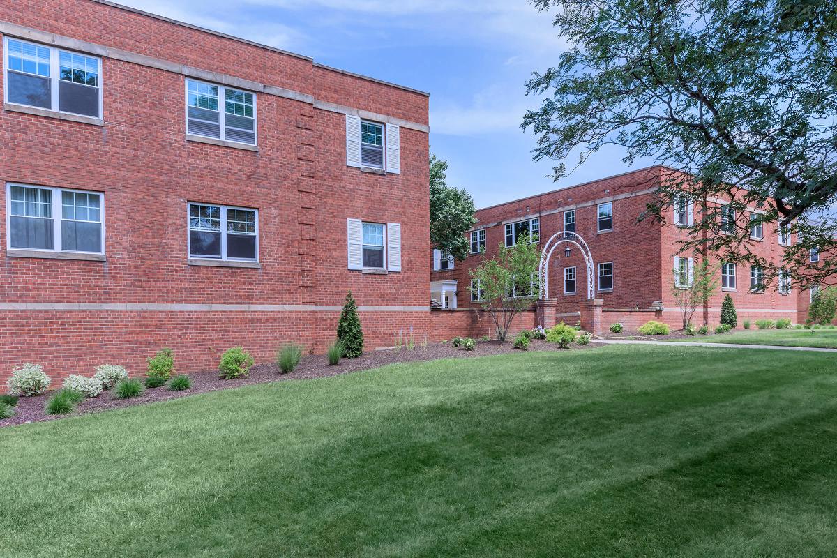 a large brick building with grass in front of a house