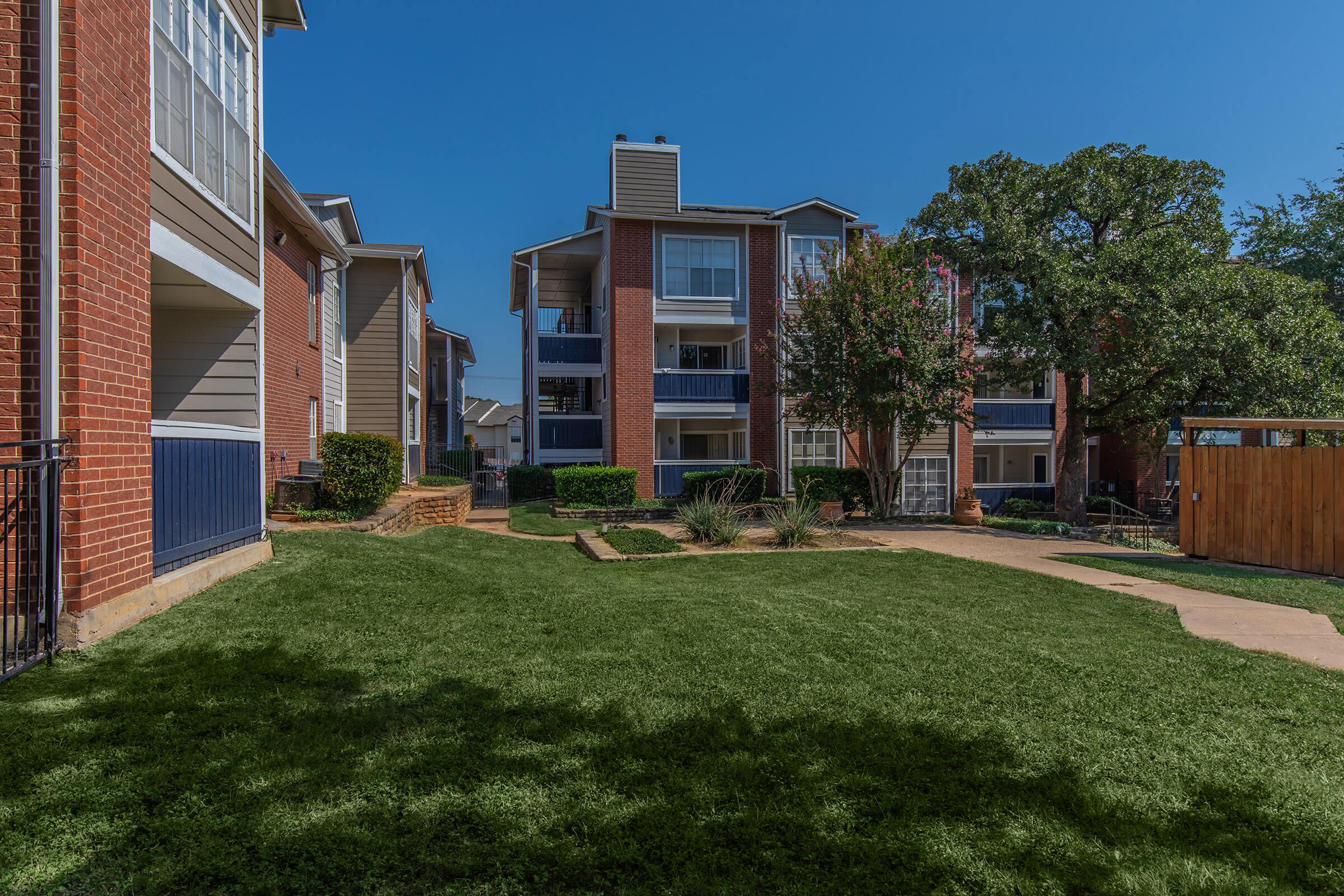 a large brick building with grass in front of a house