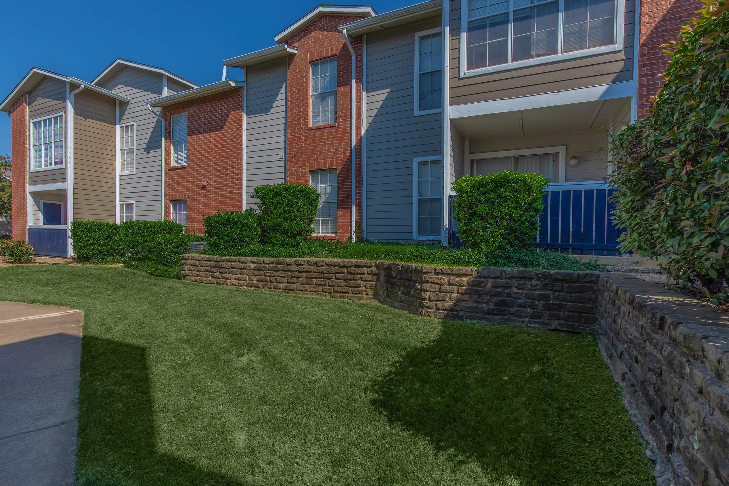 a large brick building with grass in front of a house